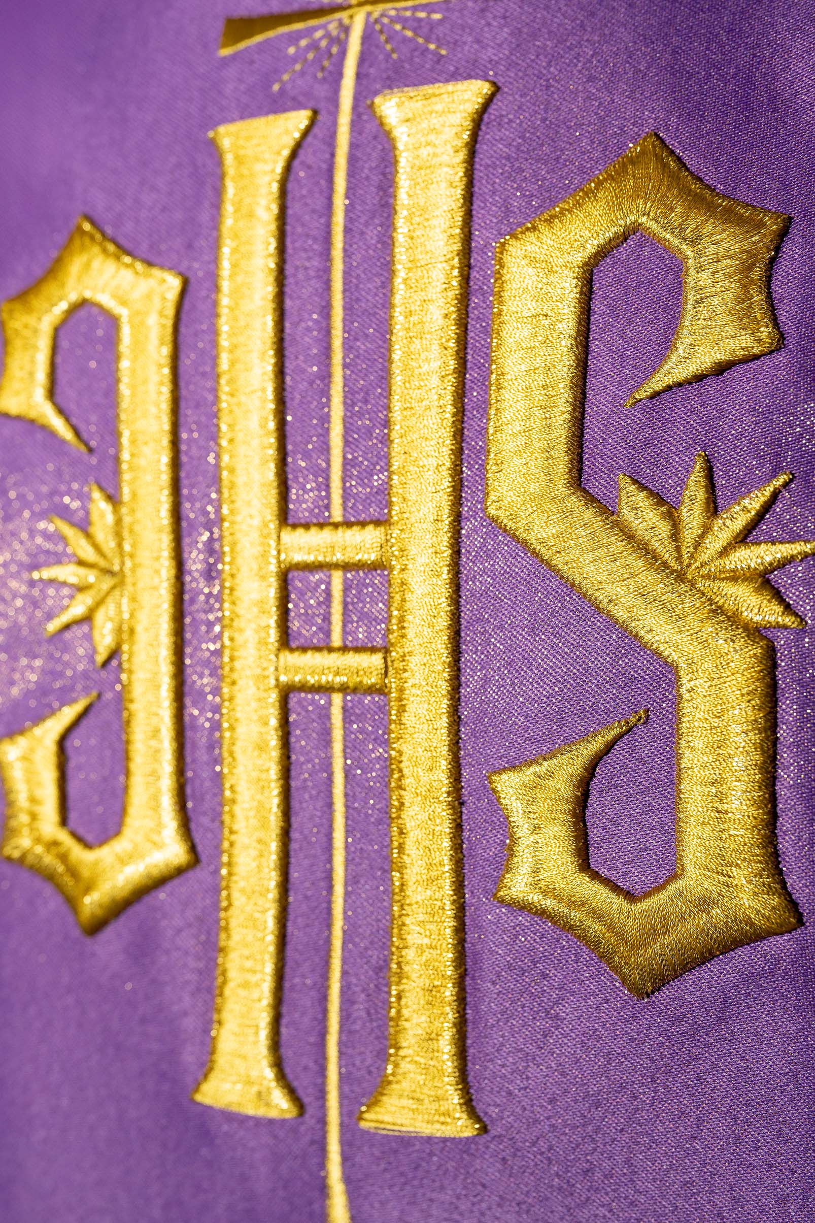 Richly decorated purple chasuble with golden motifs and a wide IHS band