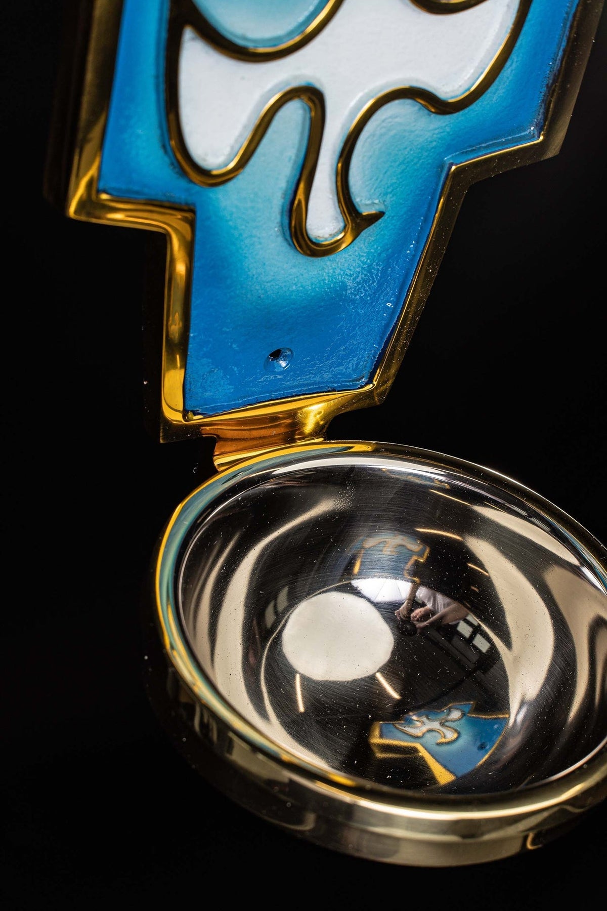 Top detail of the holy water font with silver basin and blue Holy Spirit symbol