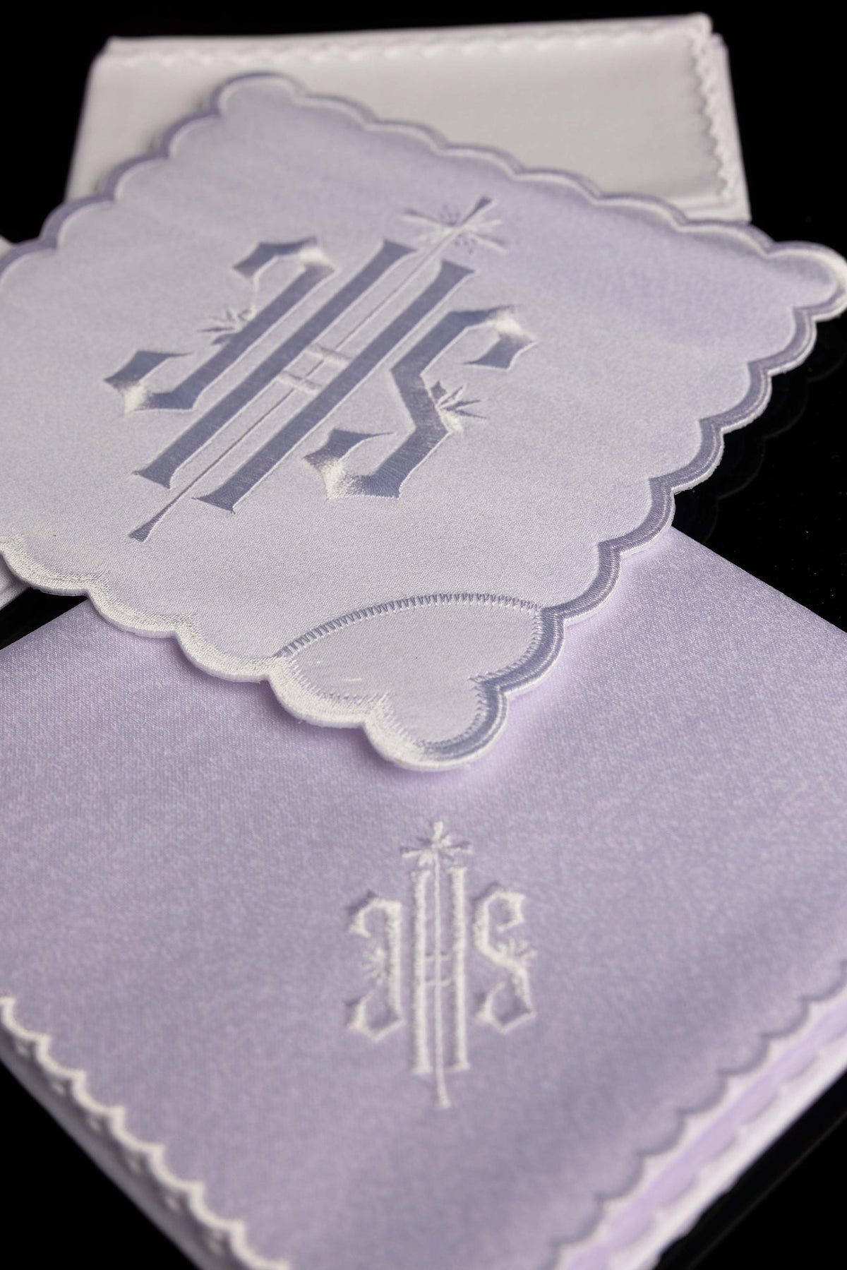 Angled view of the chalice linen set showing embroidered IHS motifs and scalloped edges