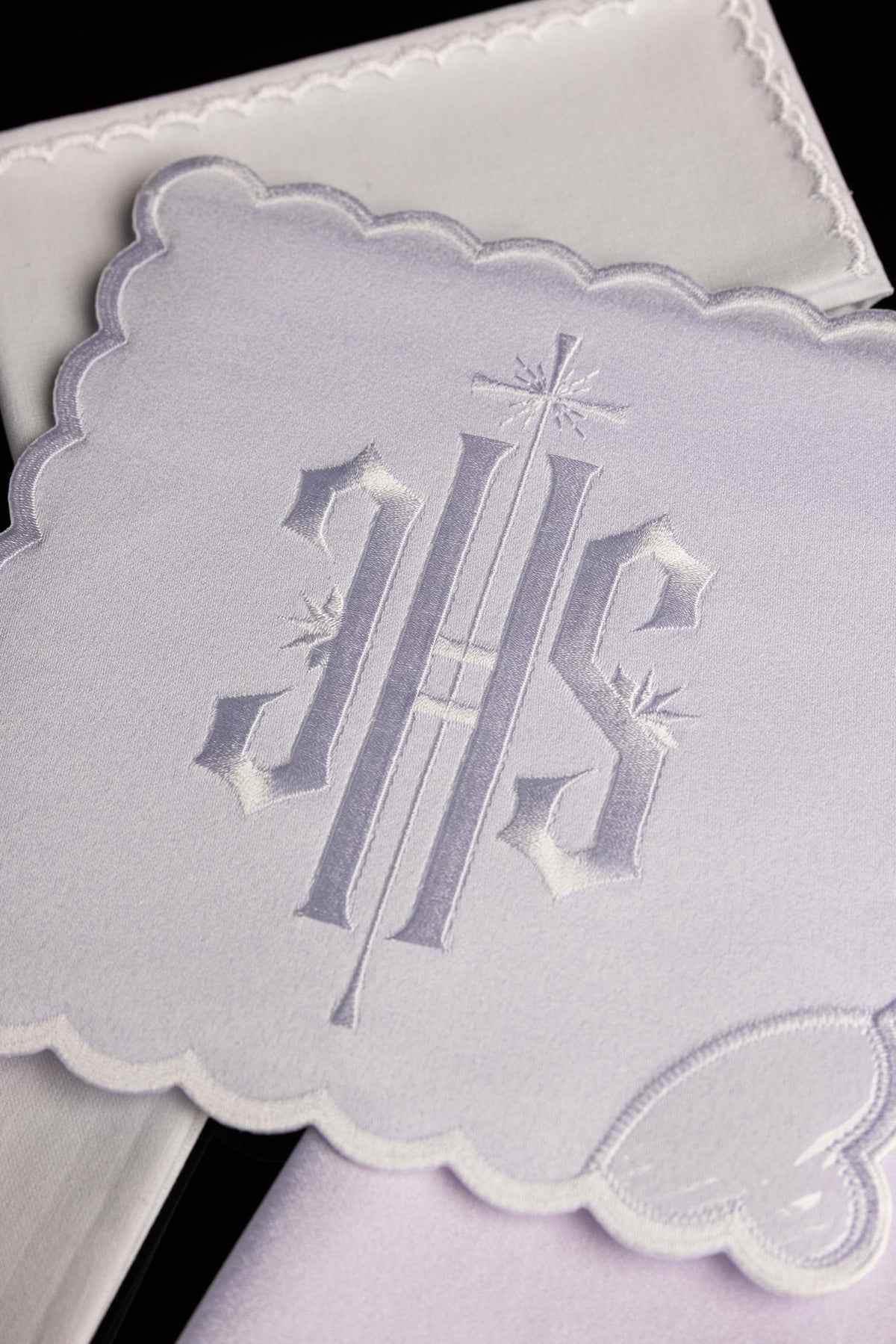 Close-up of the chalice linen set showing large IHS embroidery and scalloped white trim