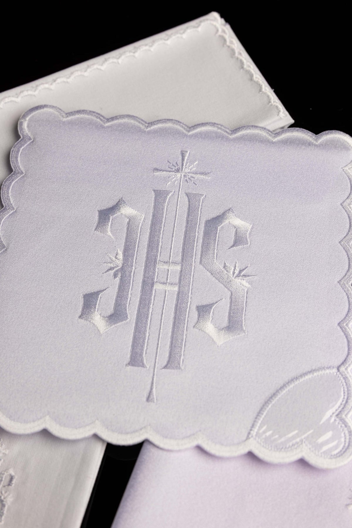 Close-up of the chalice linen set showing white IHS embroidery on a scalloped linen piece