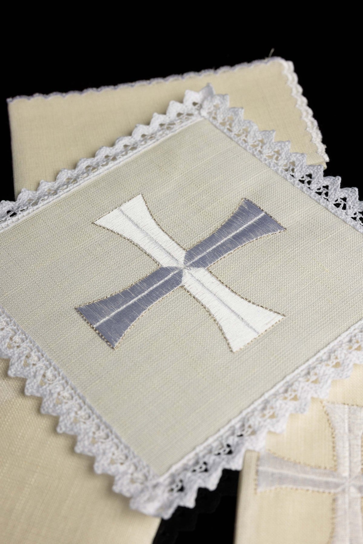 Close-up of chalice linens with delicate cross embroidery, lace edging and two-tone cross