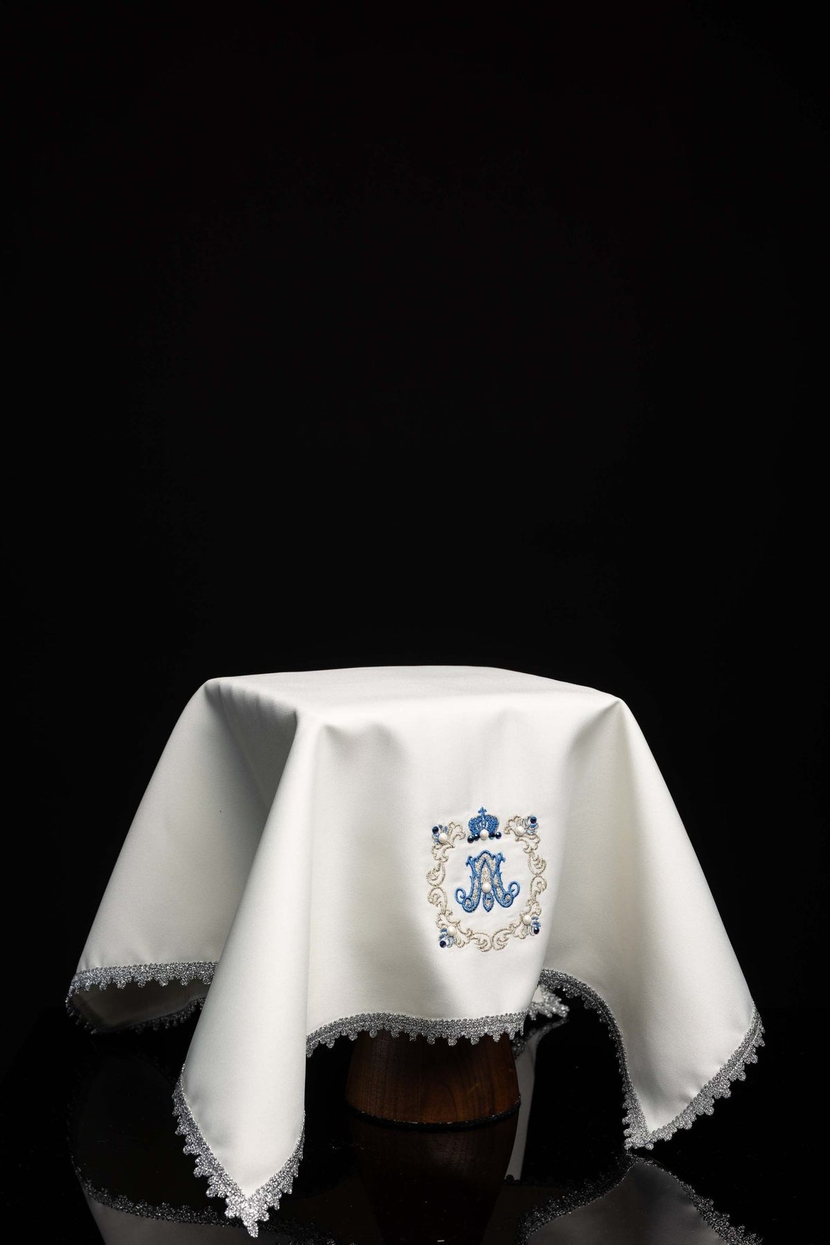 Front view of a Chalice veil with Marian embroidery, white fabric with blue Marian monogram and silver trim