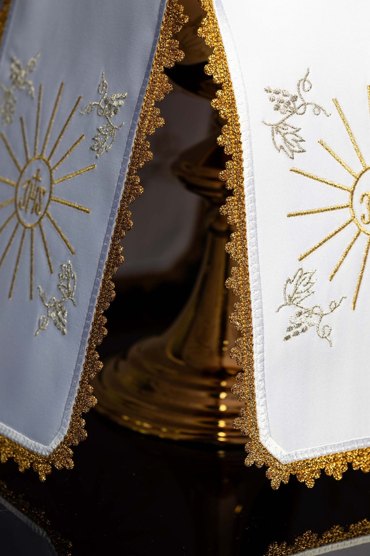 Detail view of the ciborium veil showing white and pale blue panels with gold edging and IHS motifs