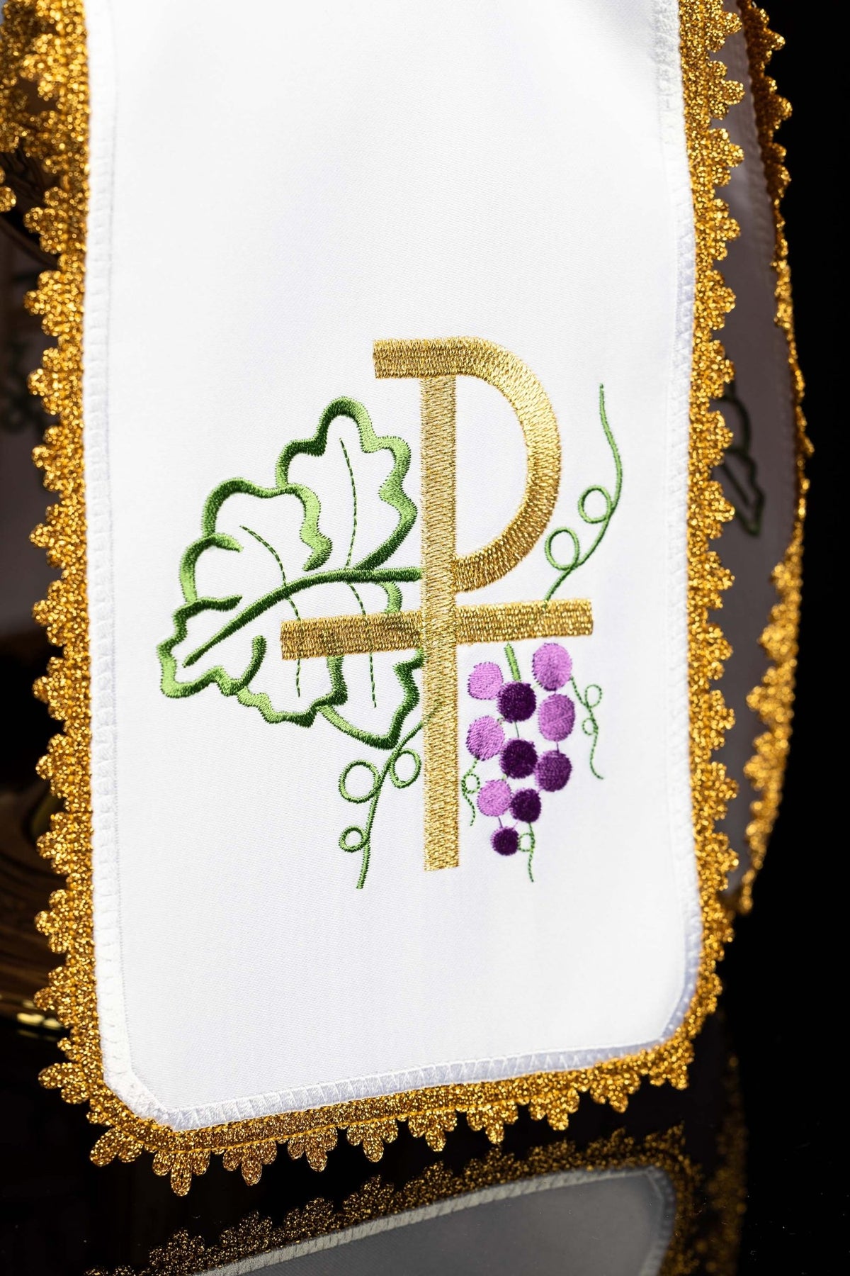 Close-up of the ciborium veil showing gold PAX embroidery, green leaves, and purple grapes