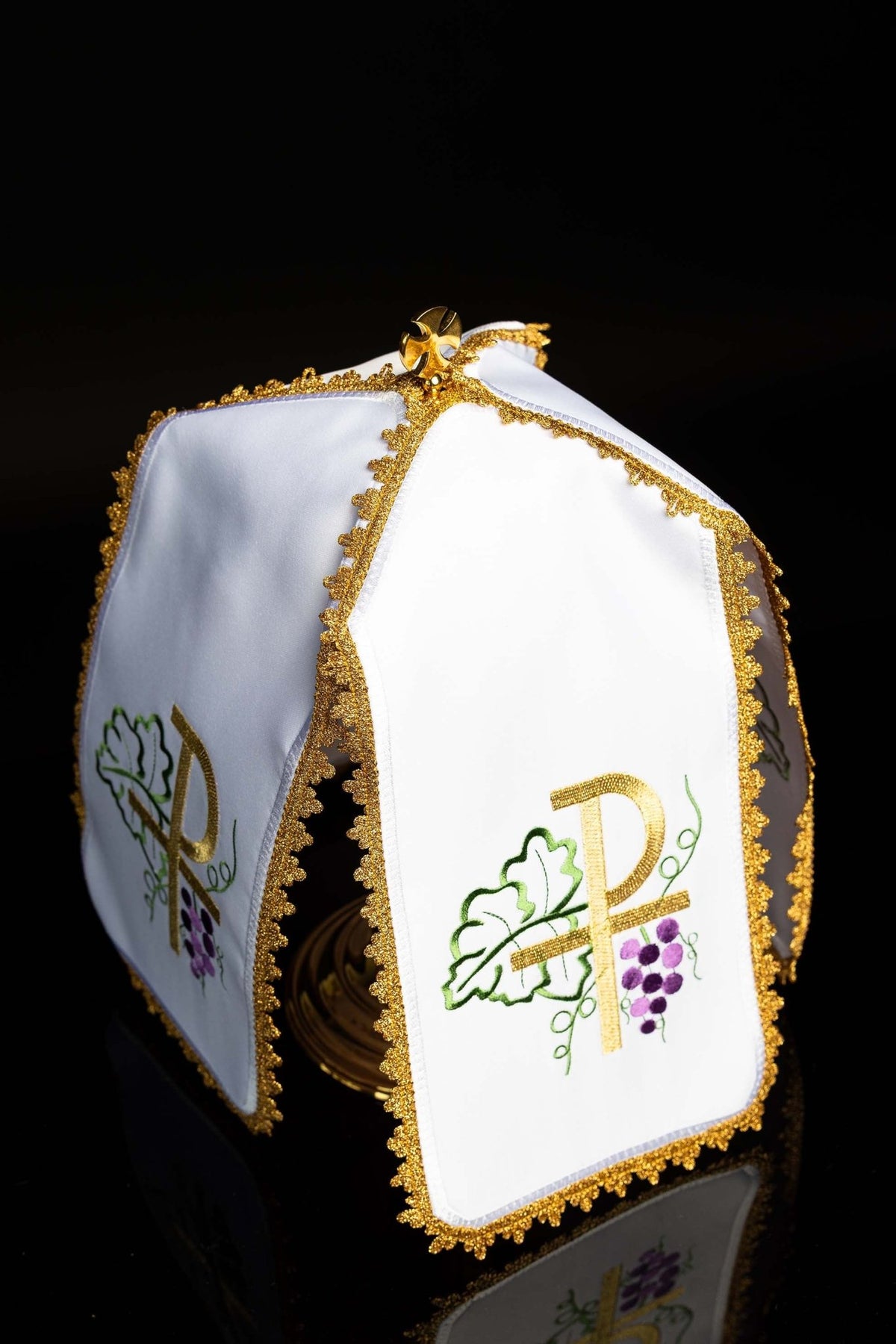 Angled view of the ciborium veil showing white panels, gold trim, and embroidered PAX motifs