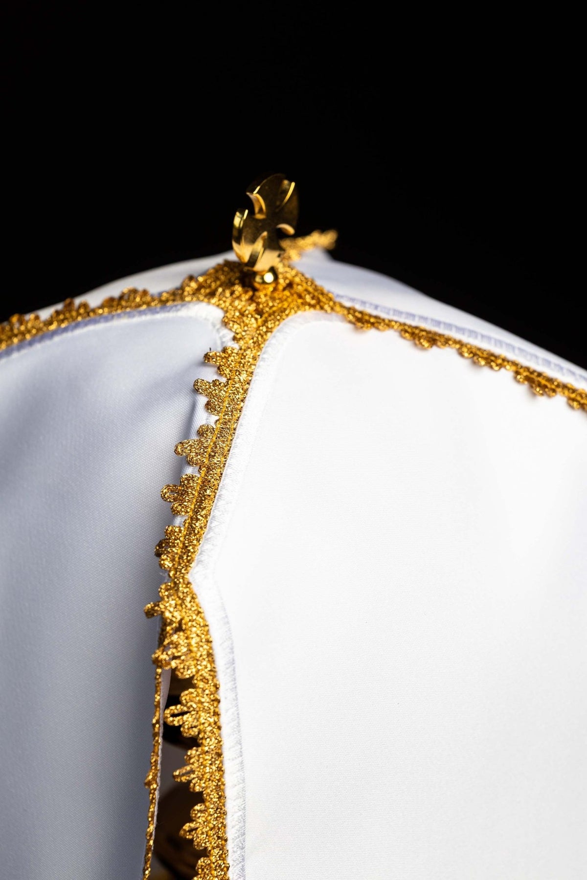 Top detail of the ciborium veil showing its gold clasp and decorative trim