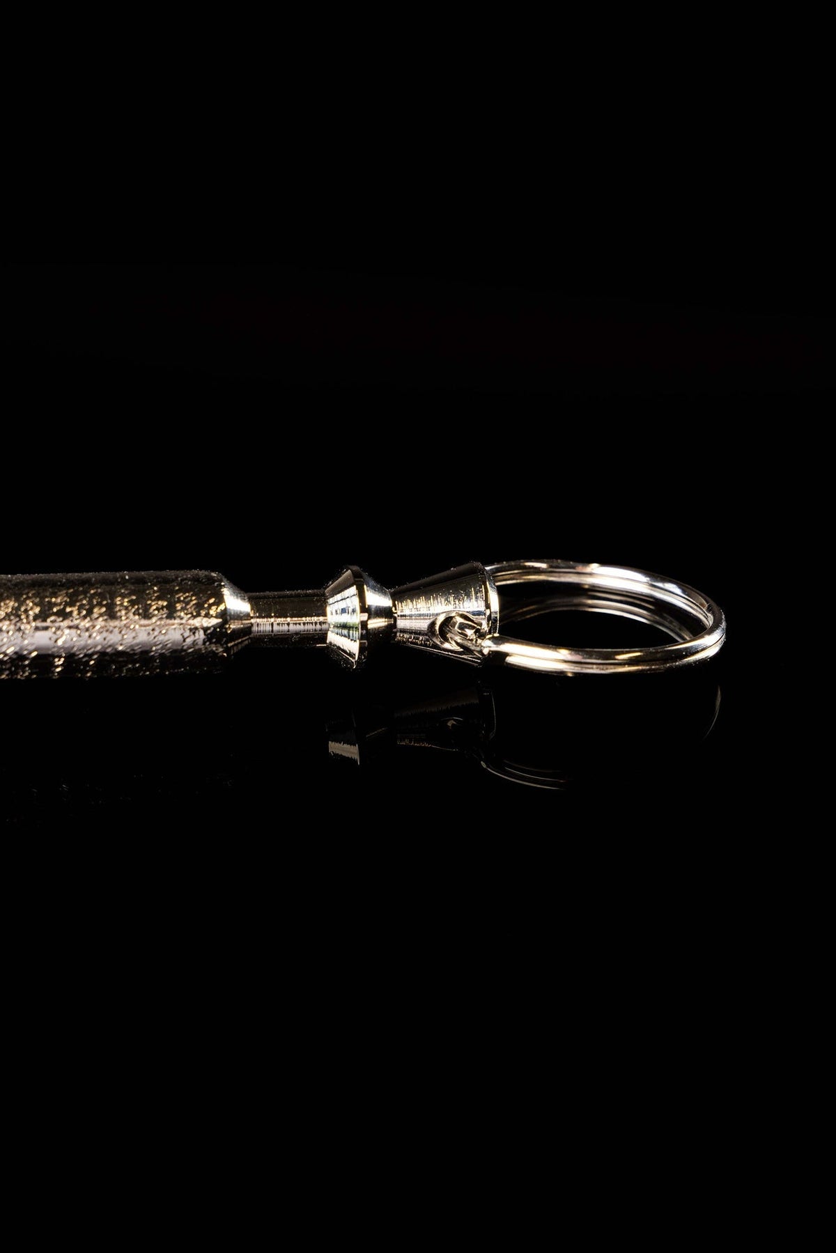Close-up of a metal aspergillum showing the polished ring attachment
