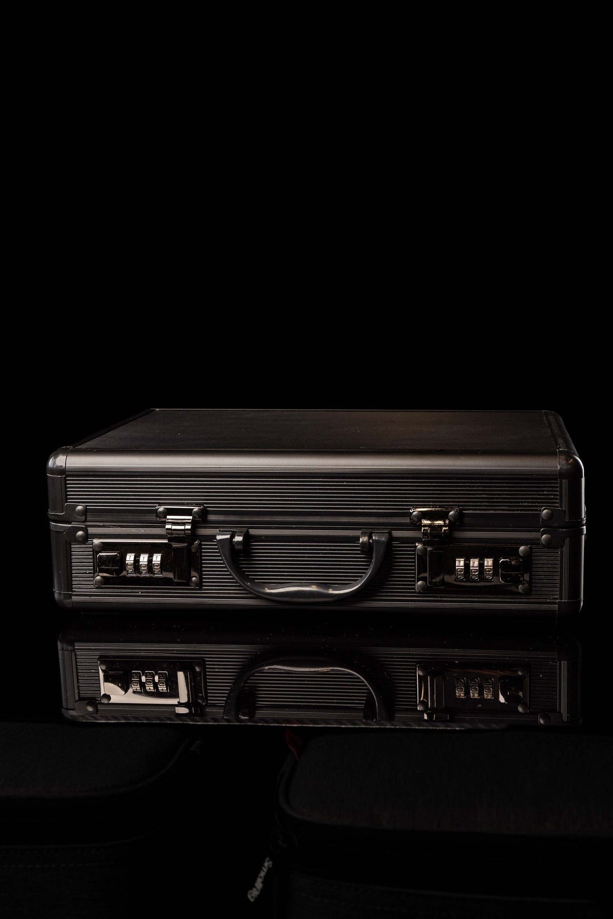 Front view of a black liturgical equipment case with ribbed aluminum panels, handle and combination locks