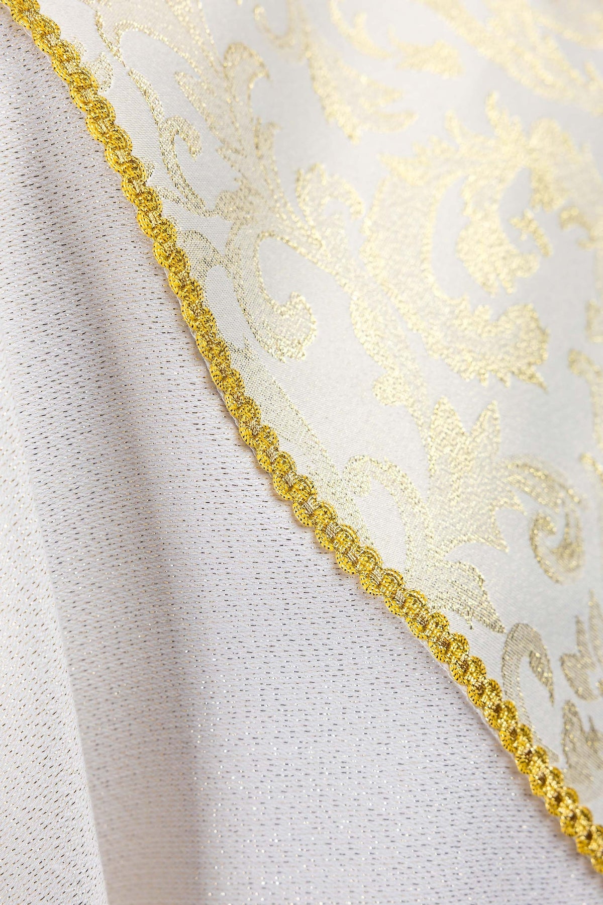 Close-up of the ecru chasuble showing jacquard fabric and gold edging