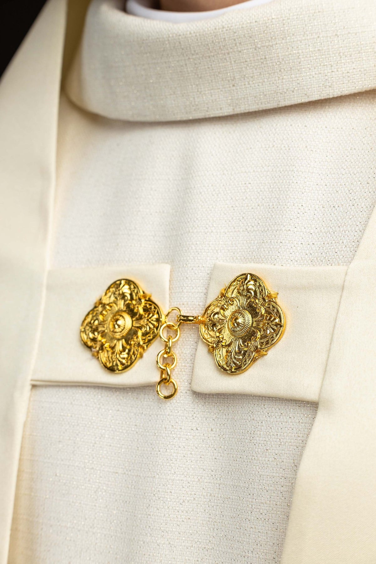 Close-up of the humeral veil clasp showing ornate gold medallions and chain