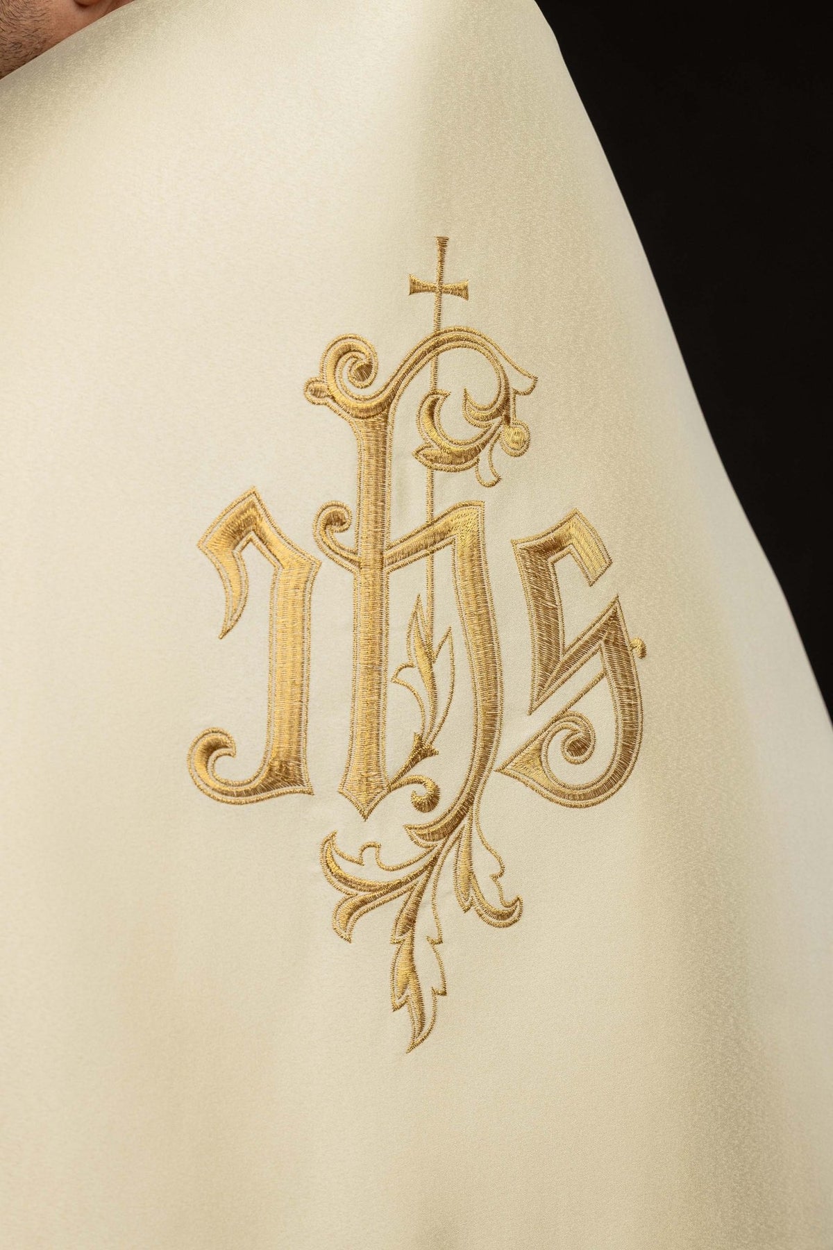 Close-up of the ecru humeral veil showing ornate gold embroidered IHS motif