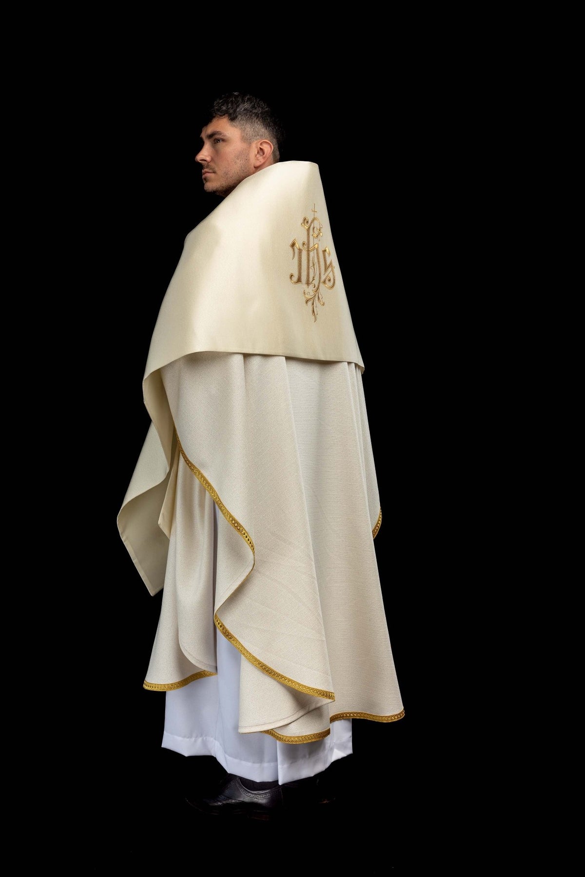 Side worn view of the ecru humeral veil showing embroidered IHS motif and gold edging