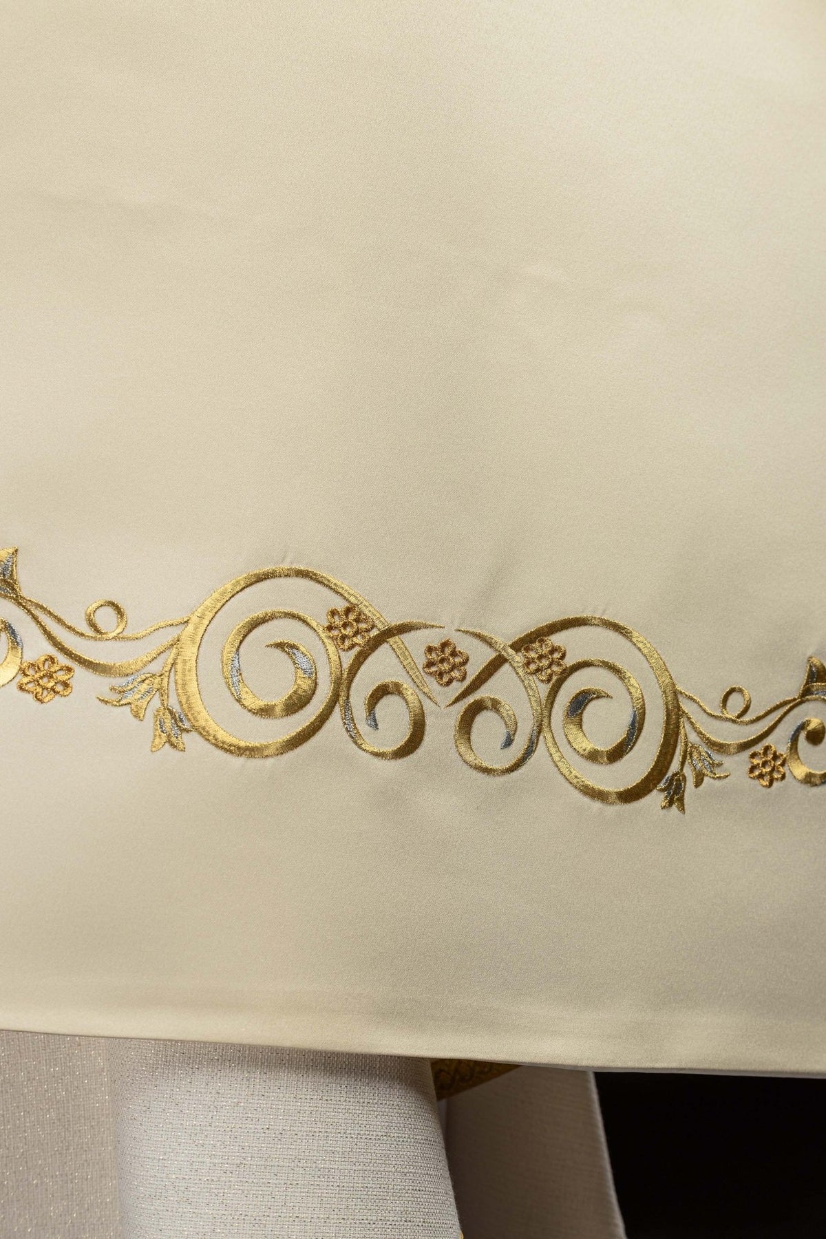 Close-up of the humeral veil showing gold scroll embroidery near the hem
