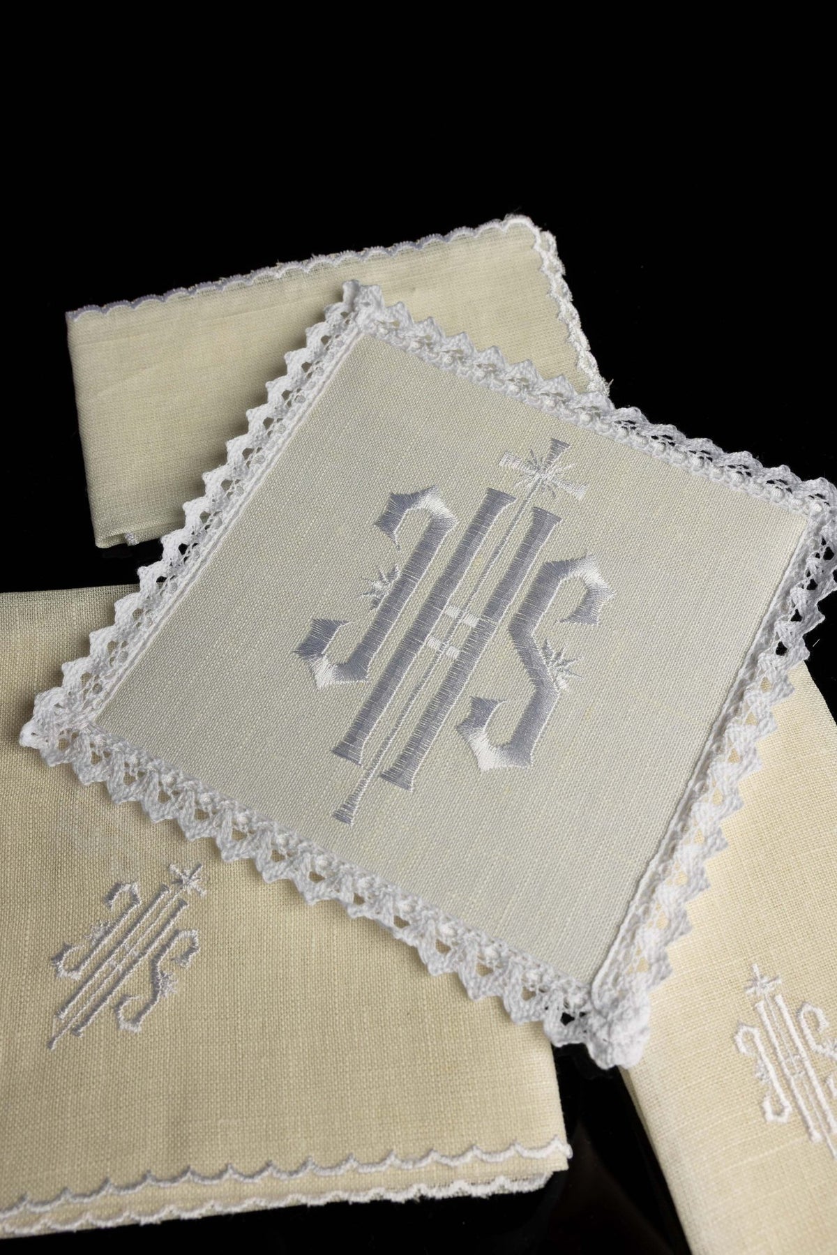 Folded altar linen set with central IHS embroidery and lace border