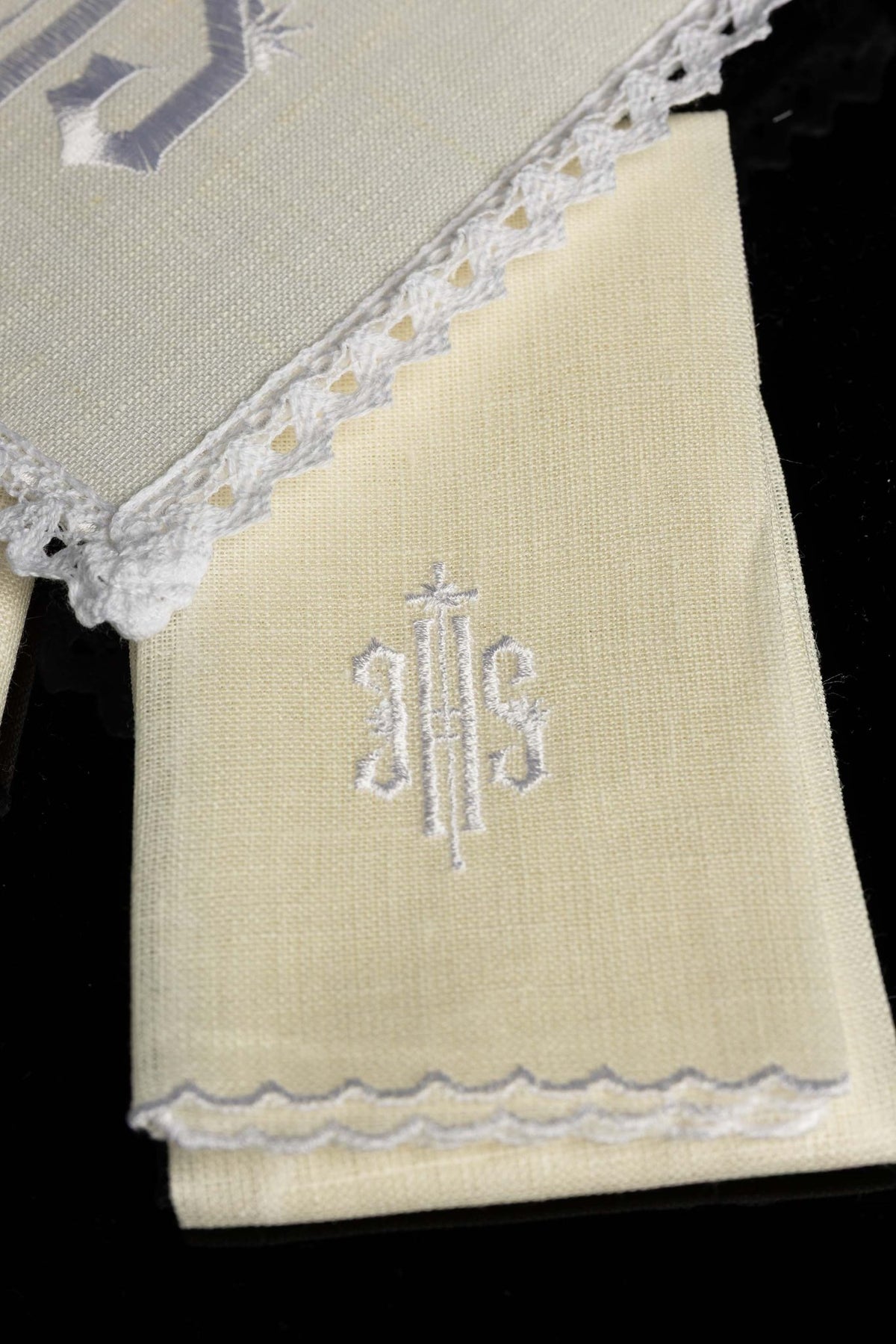 Close-up of altar linen panel with white IHS embroidery and scalloped trim
