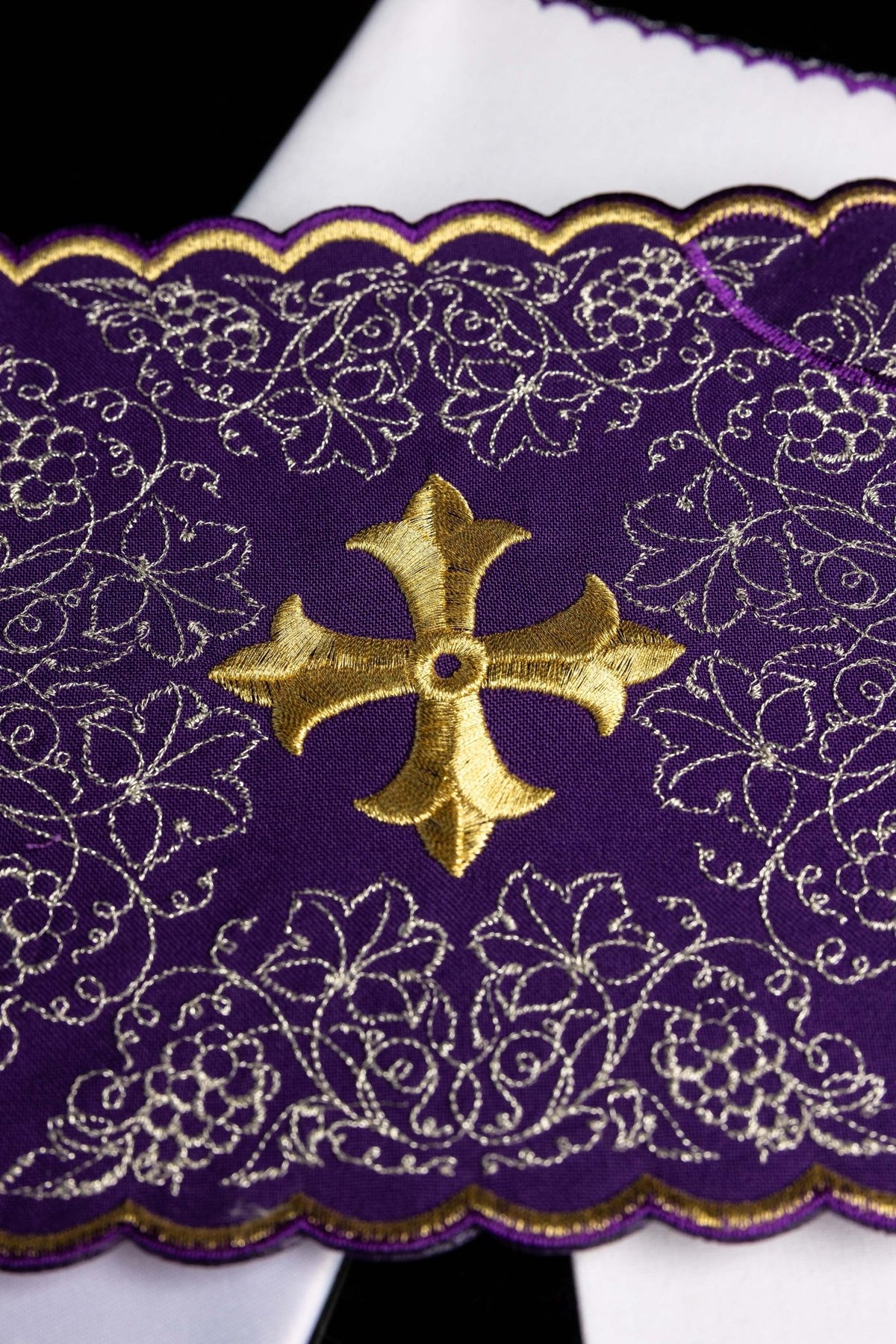 Close-up of chalice linens set with a purple cross motif, showing floral embroidery around the gold cross