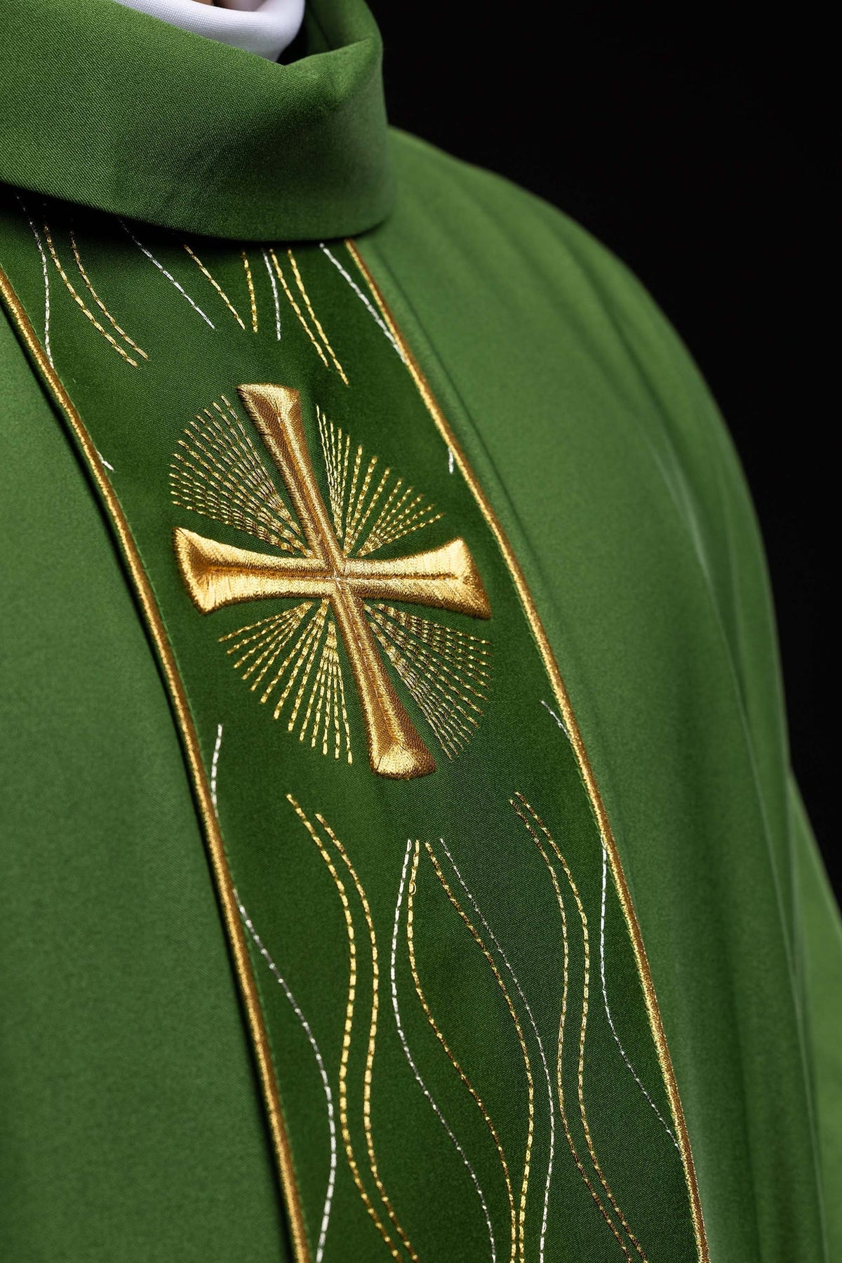 Close-up of the green chasuble's gold cross embroidery and radiating stitched design