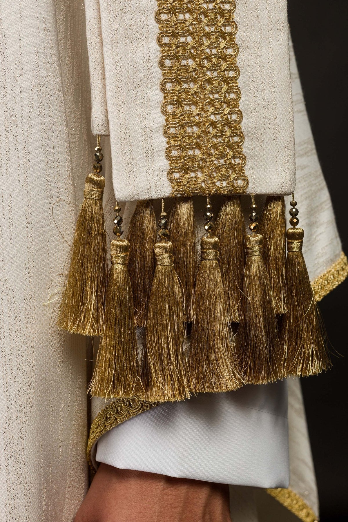 Close-up of ecru chasuble's long gold-trimmed band and tassels