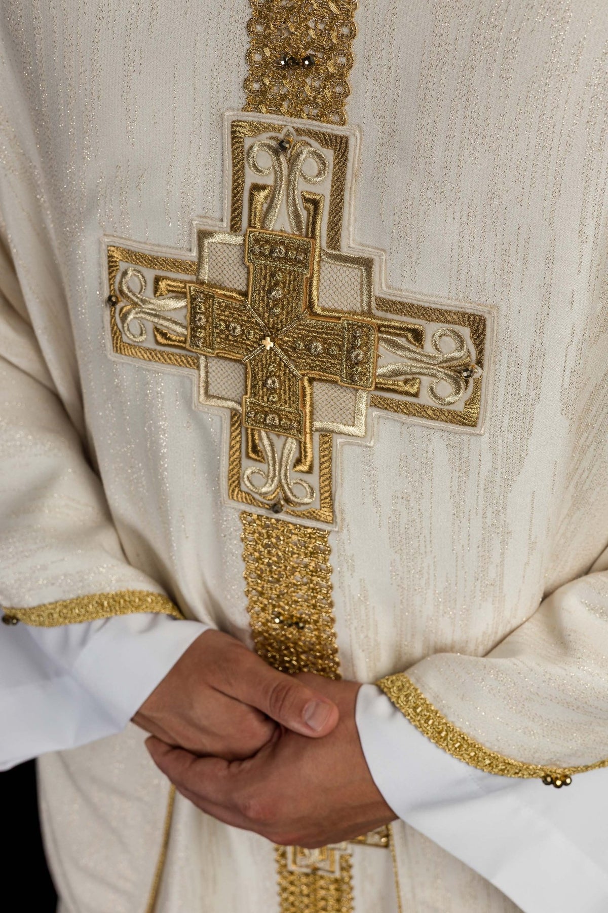 Worn view of ecru chasuble with embroidered cross and gold edging