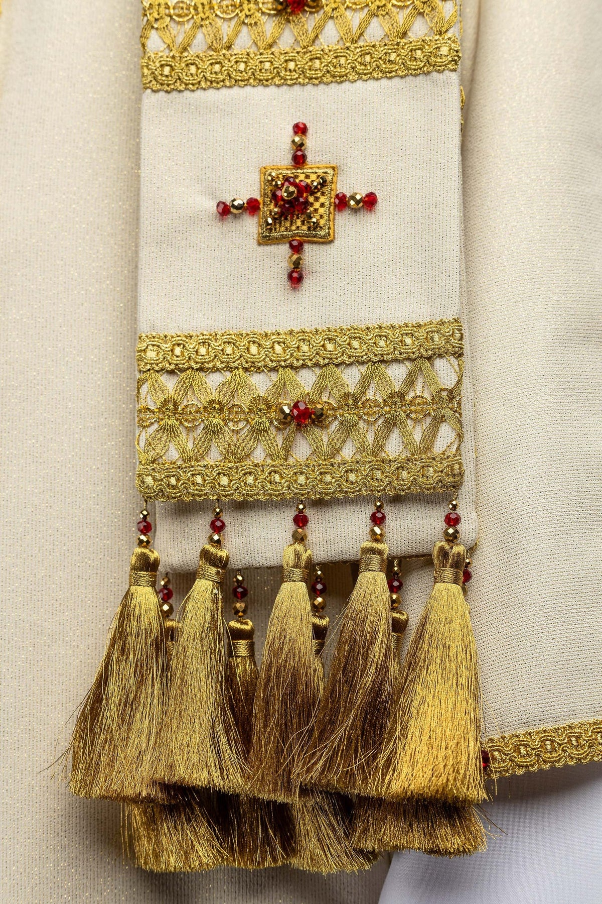 Close-up of the chasuble sleeve with jeweled cross, openwork trim, and gold tassels