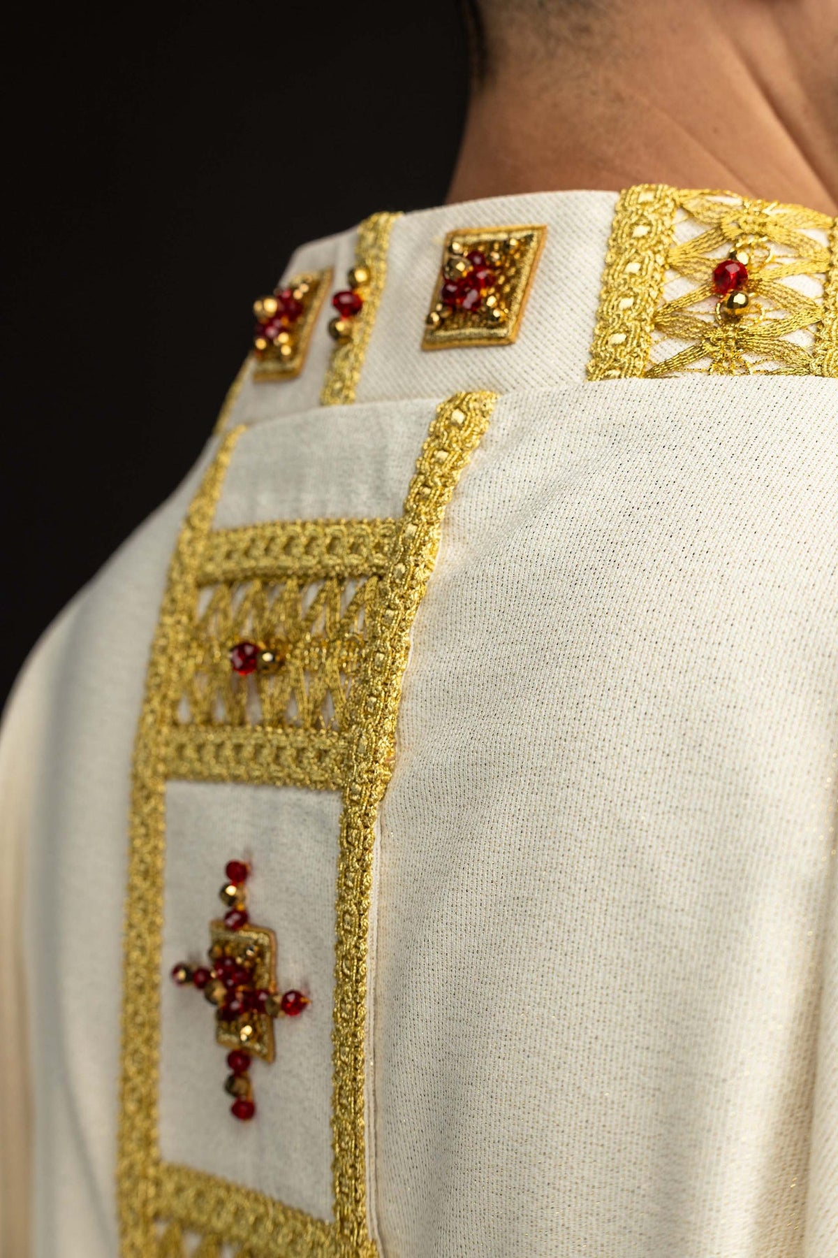 Close-up of the white handmade chasuble with gold trim and red stone embellishments