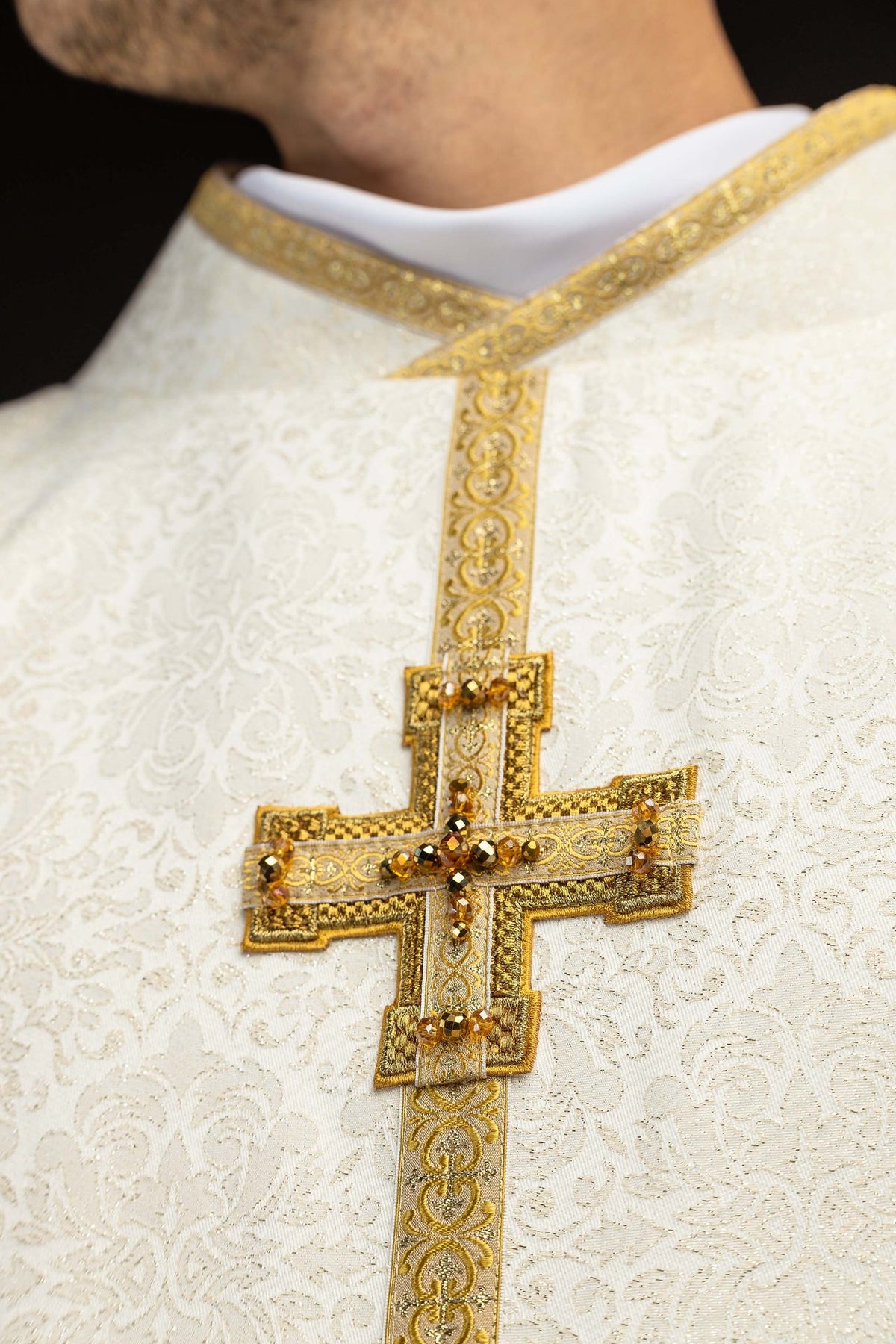 Close-up of the chasuble collar and upper gold cross with amber stones