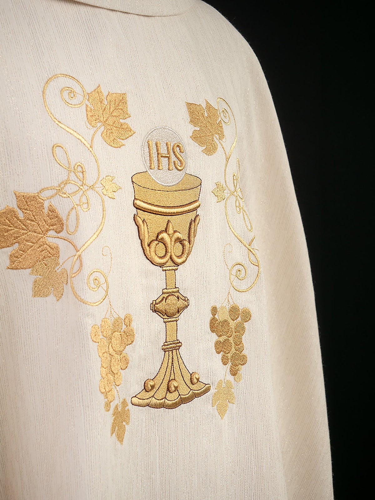Close-up of ecru chasuble with embroidered gold chalice, IHS and grapevines