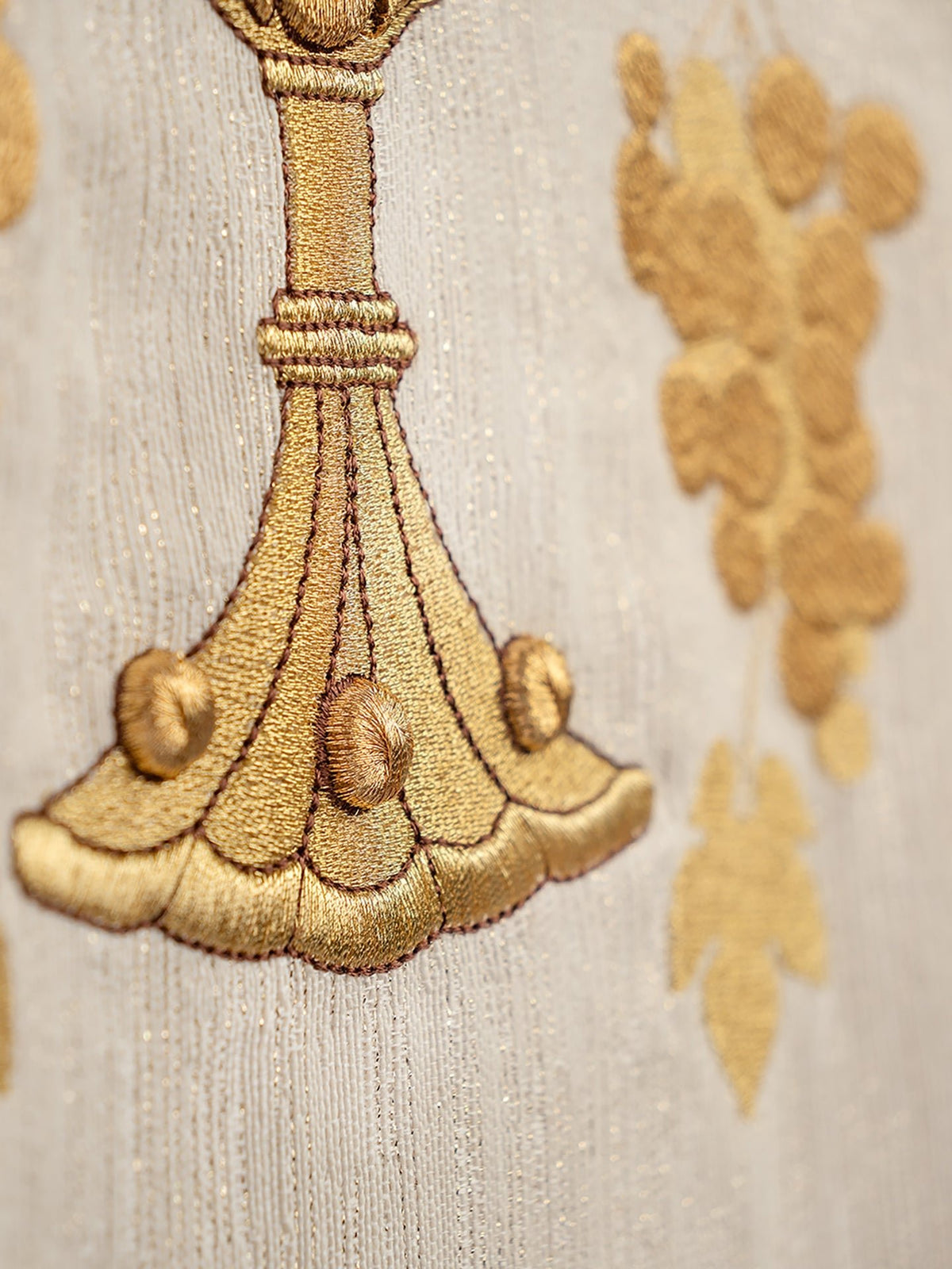 Close-up of ecru chasuble showing embroidered chalice base and grapevine details