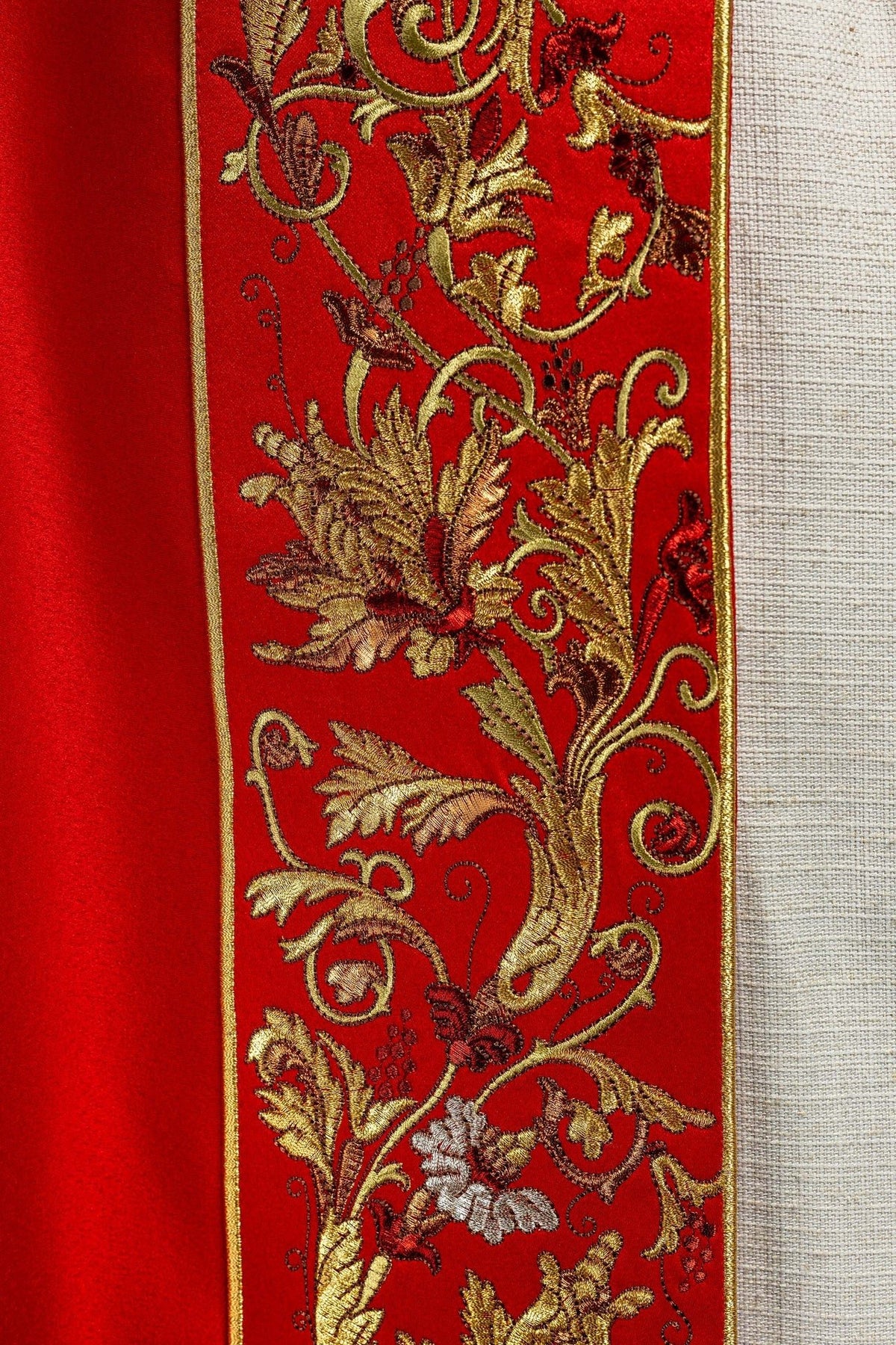 Close-up of floral embroidery on the red cope, with gold leaves and multicolor flowers