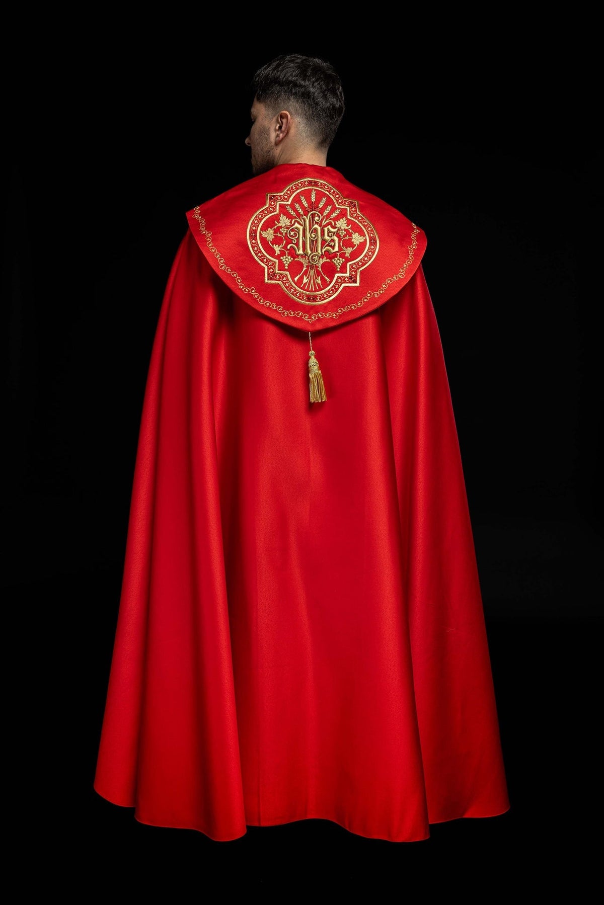 Close-up of red cope showing its gold hanging tassel beneath the embroidered back panel