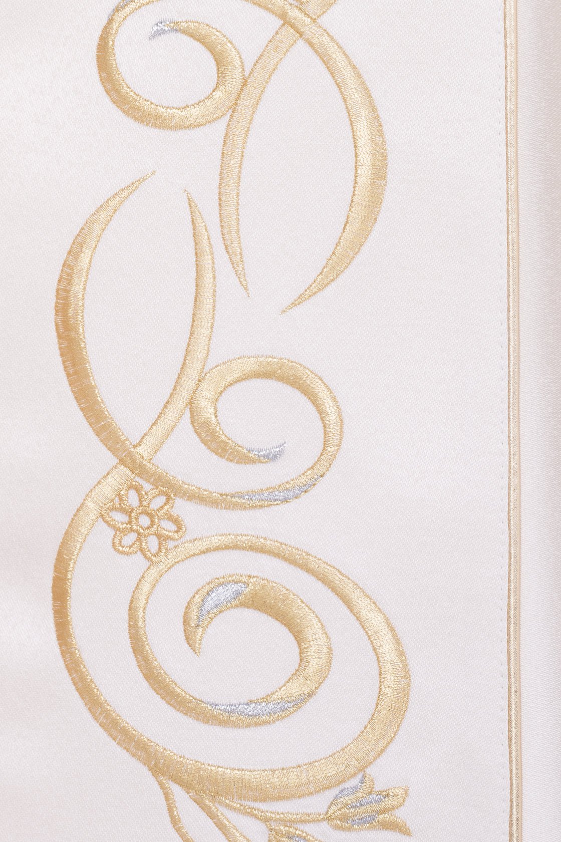 Close-up of ecru liturgical cope showing gold scroll embroidery with silver accents