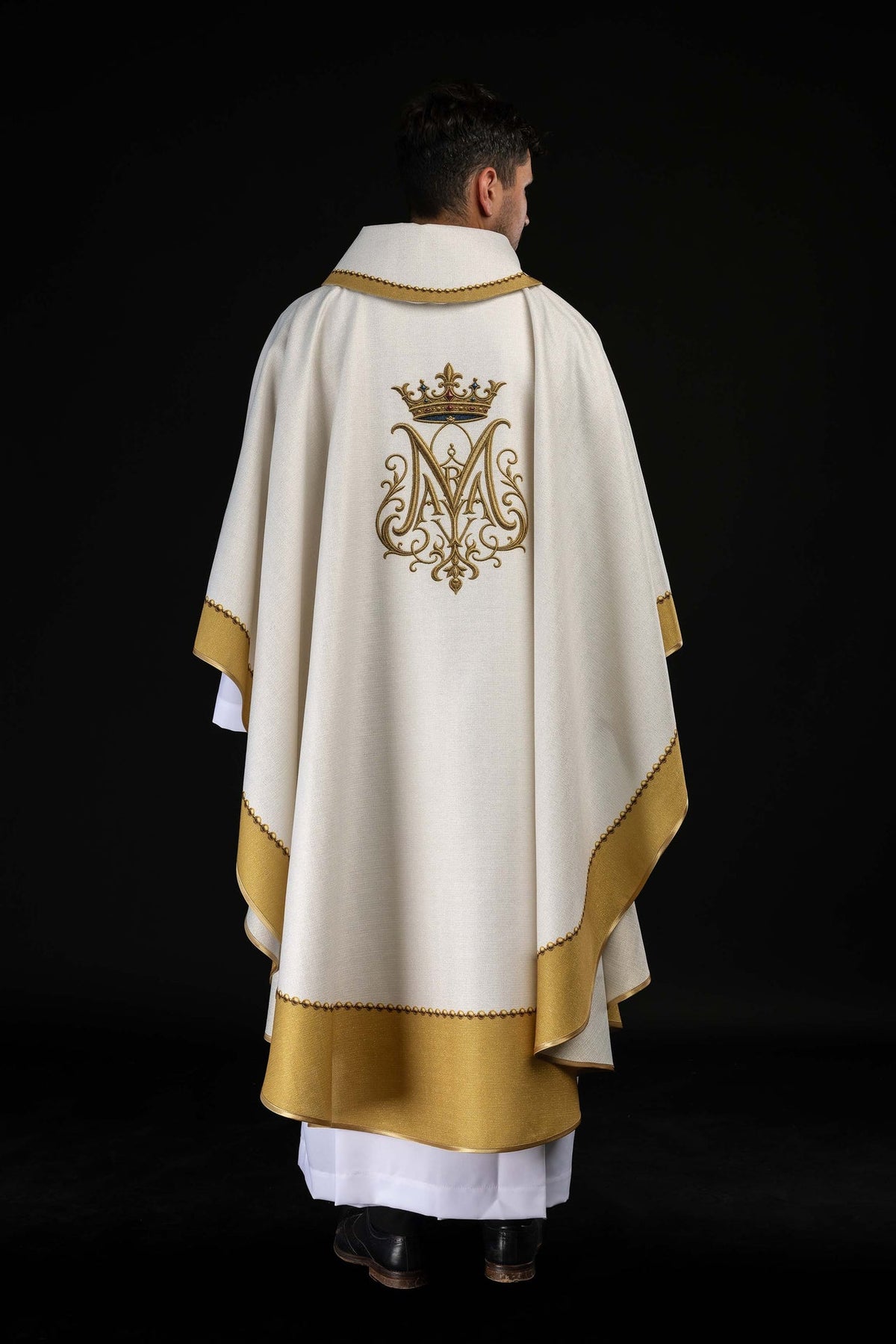 Full back view of the white chasuble with gold trim and Marian monogram