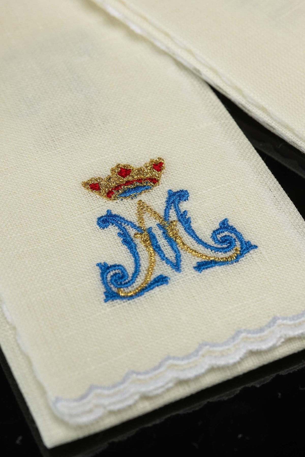 Detail of linen purificator with crowned blue Marian motif, gold embroidery and scalloped edge