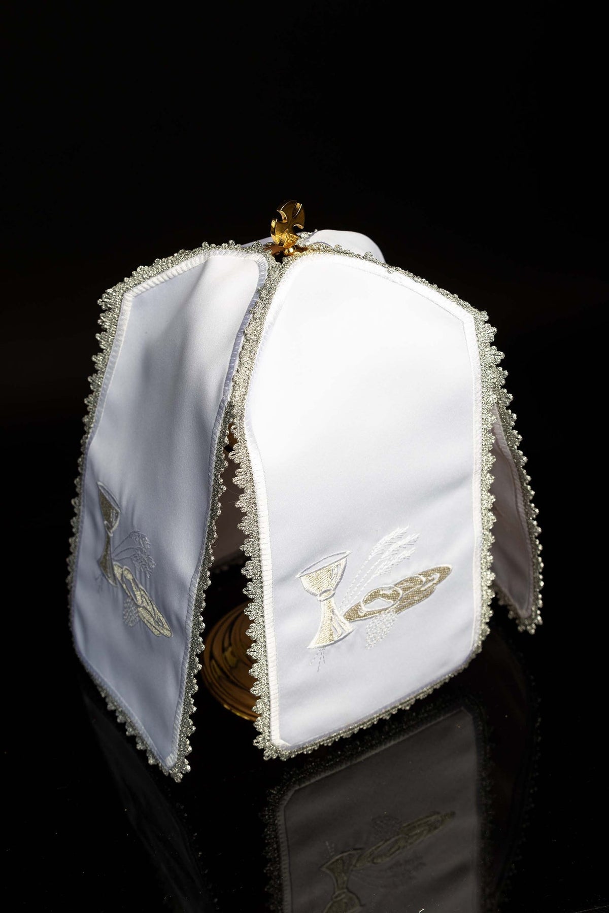 Angled view of the white ciborium veil with Eucharistic embroidery and silver edging