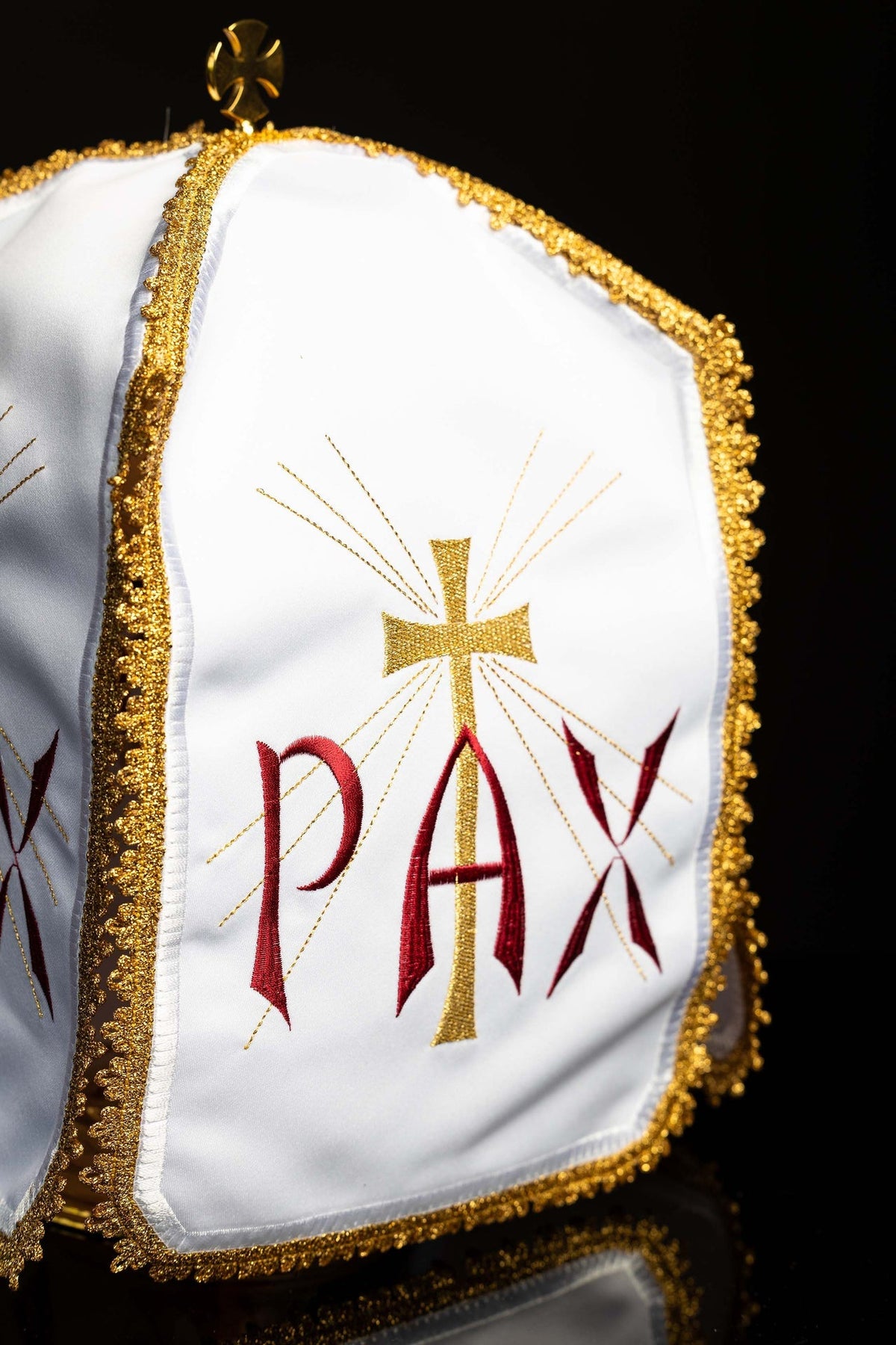 Angled view of the ciborium veil showing gold trim, cross, radiant rays and red PAX embroidery