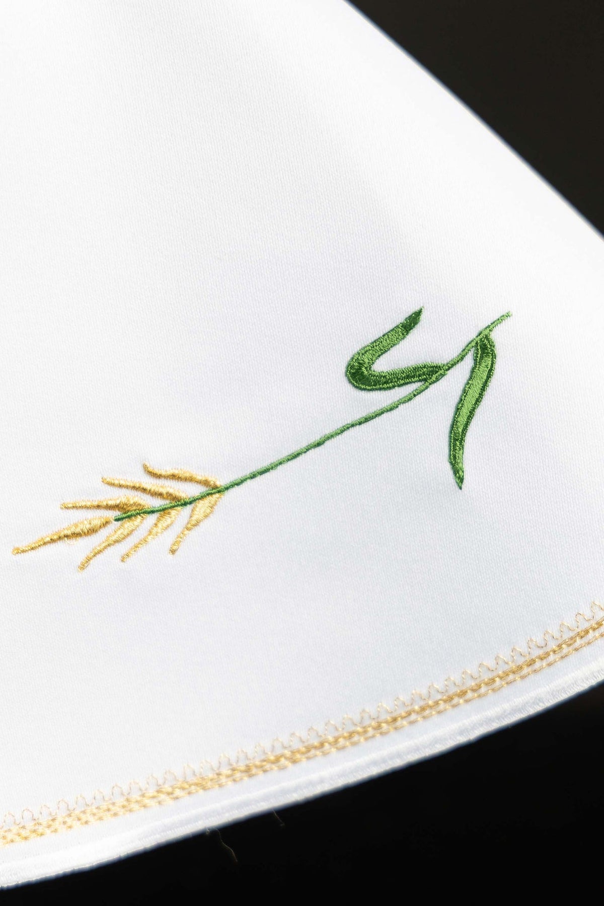 Detail view of the ciborium veil showing green wheat-stem embroidery and gold edging