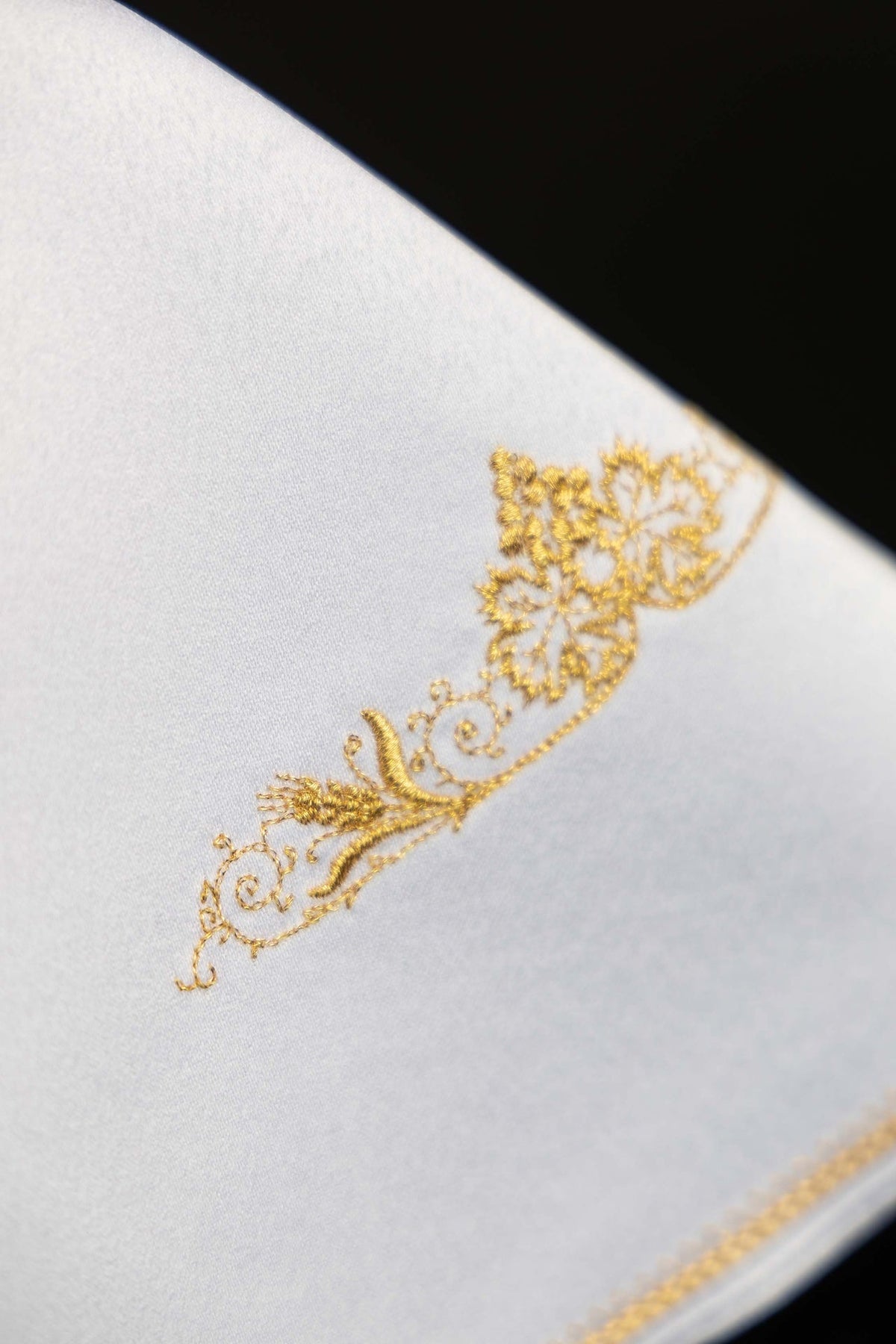 Close-up of gold floral embroidery on the white ciborium veil
