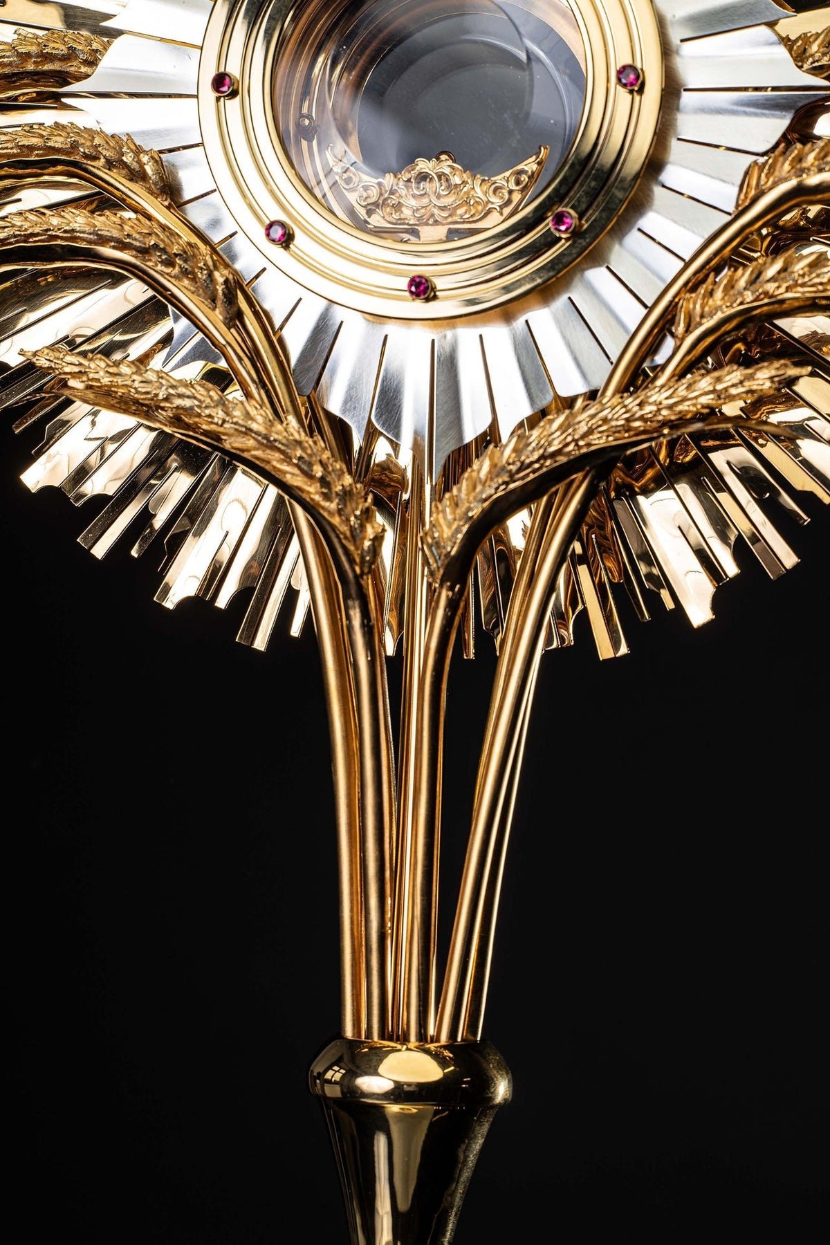 Lower detail of gilded brass monstrance showing gold stem and polished support