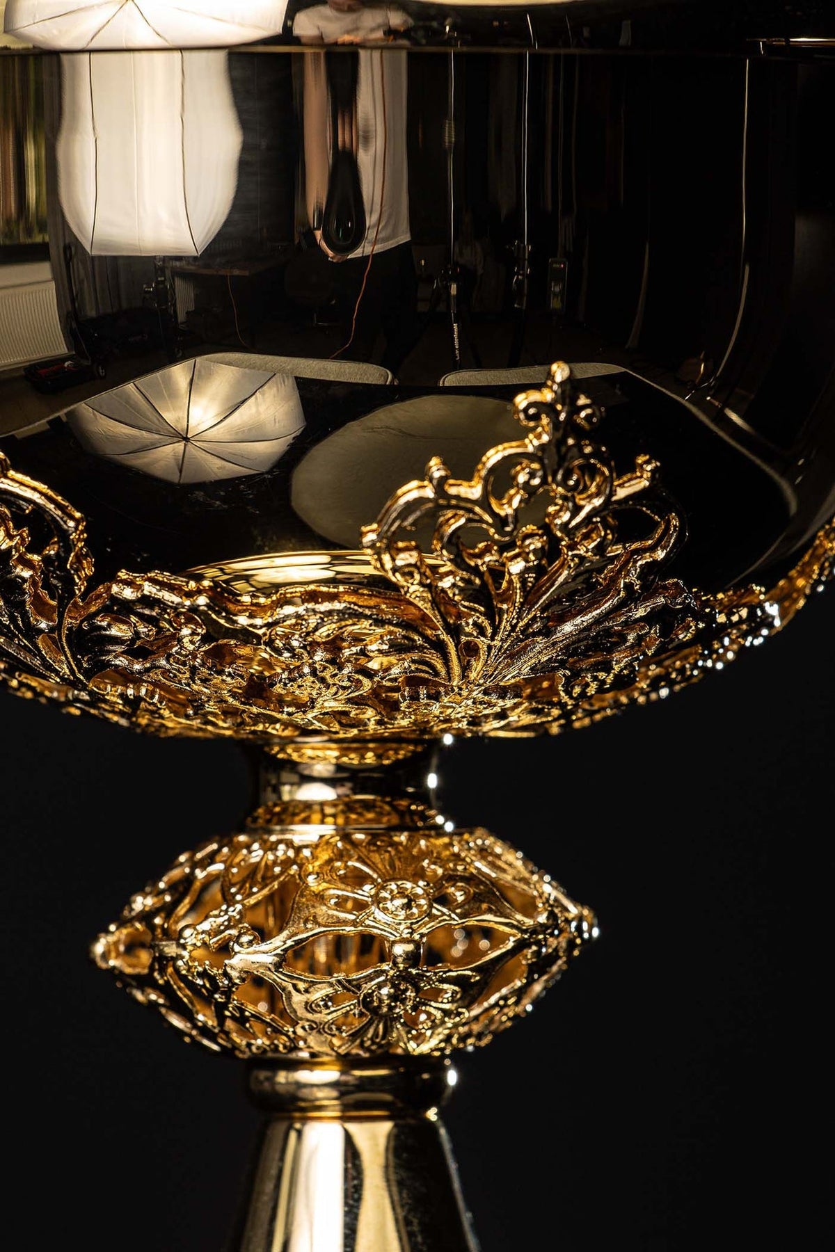 Close-up of gilded brass ciborium showing floral relief around the bowl and ornate stem