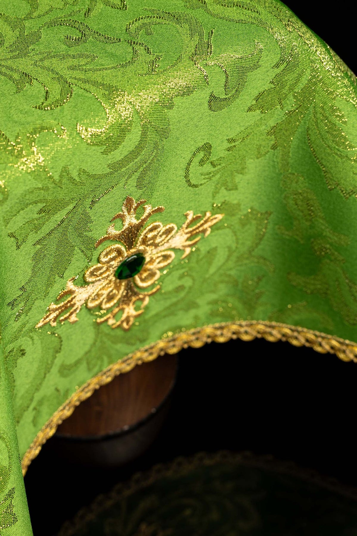 Angled view of the green chalice veil with embroidered gold cross, stone, and gold trim