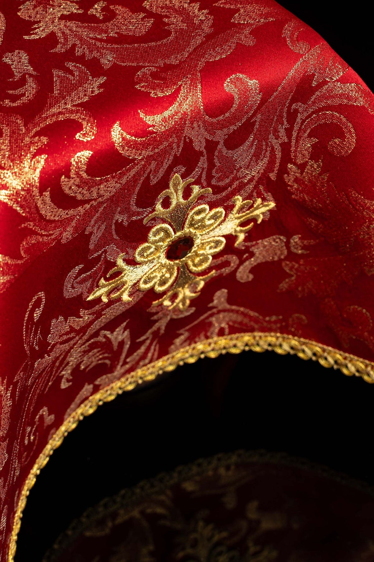 Angled close-up of a red chalice veil with embroidered gold cross and gold trim