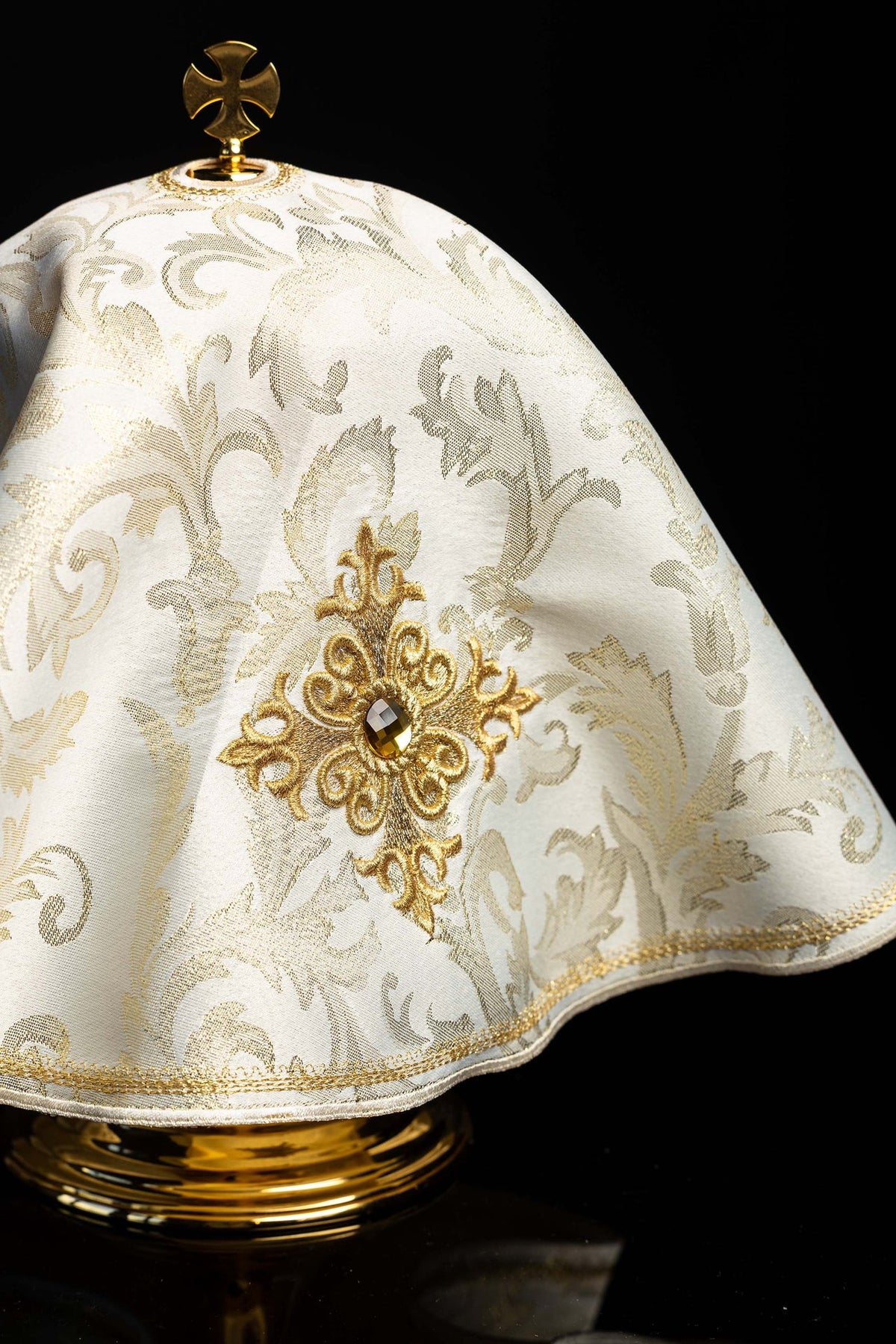 Upper view of the ciborium veil showing the gold cross finial and embroidered motif
