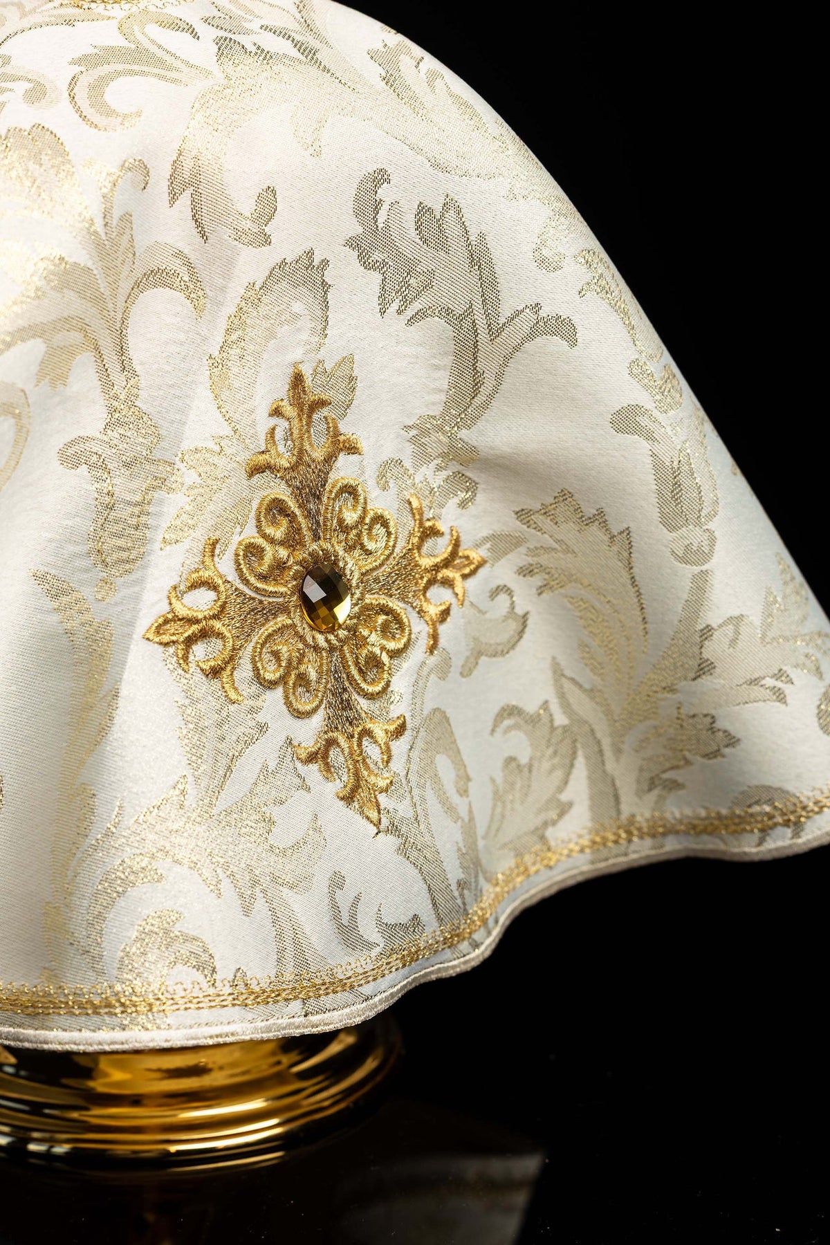 Close-up of the ciborium veil showing embroidered gold cross and decorative stone