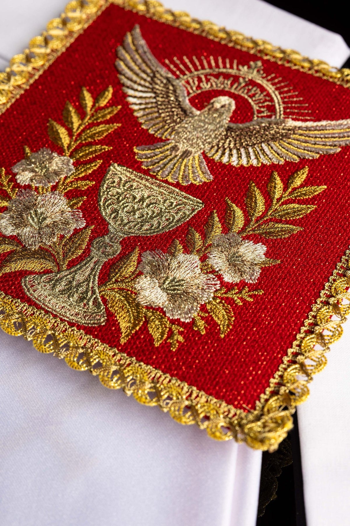 Detail view of the altar linen set showing embroidered Holy Spirit and Communion Chalice on red fabric