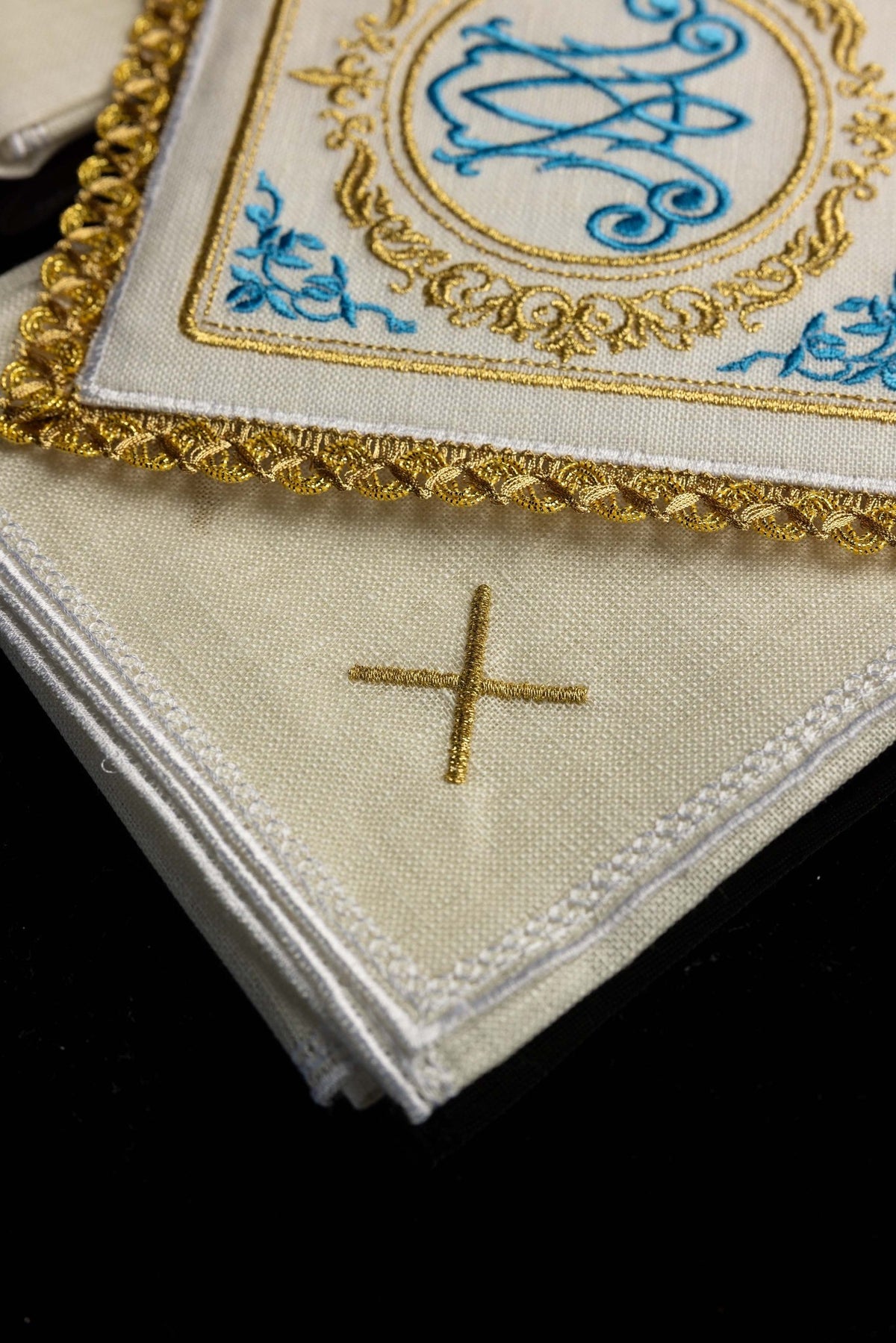 Close-up of Marian altar linens set showing a gold embroidered cross and white edging