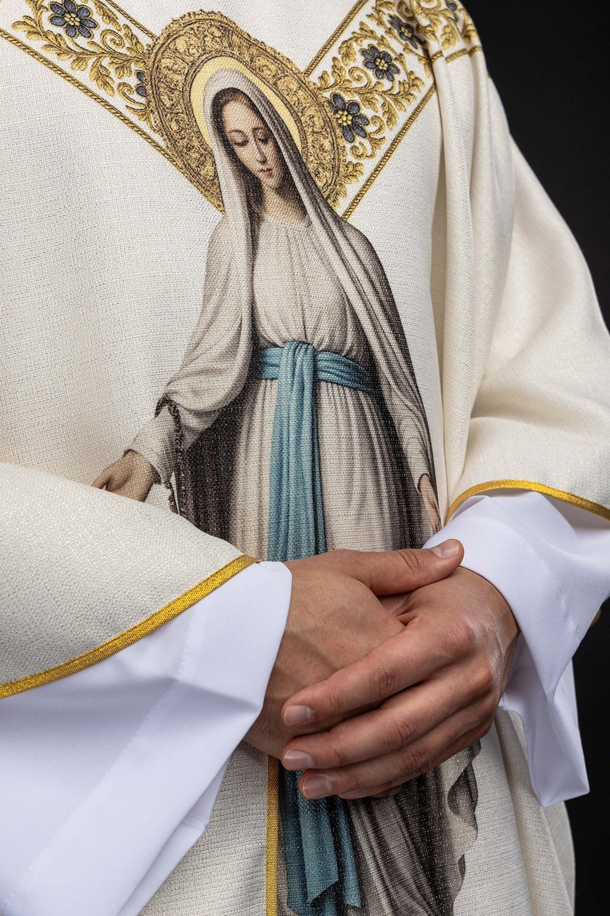 Worn detail of the chasuble showing gold edging and Our Lady of Lourdes print