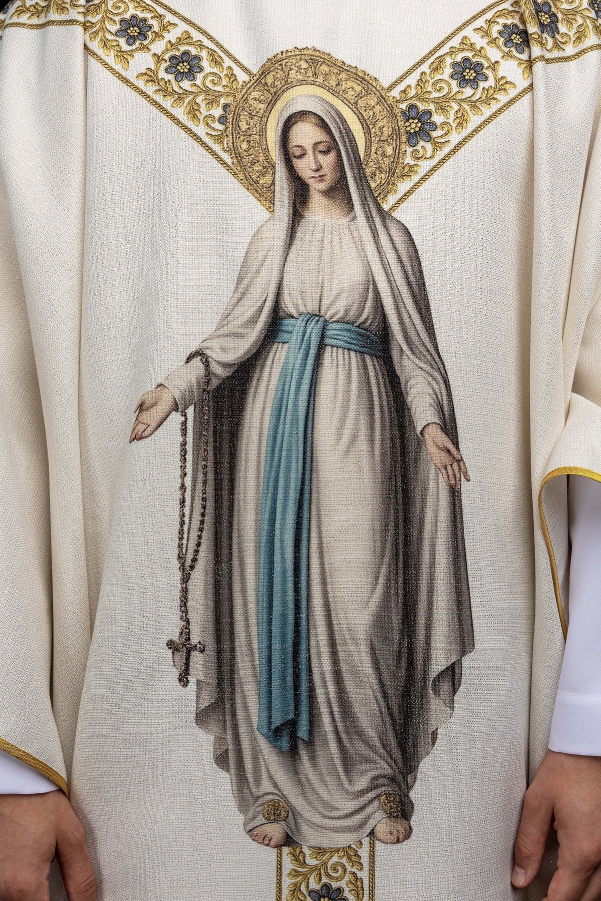 Close-up of the chasuble showing Our Lady of Lourdes with a blue sash and rosary