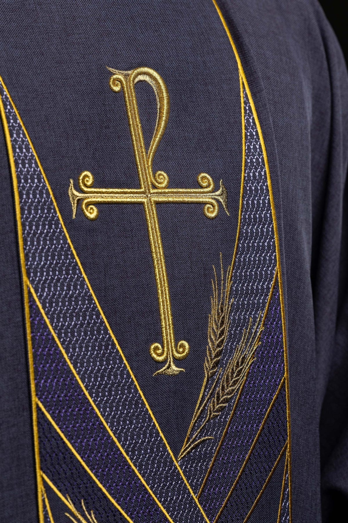 Close-up of the purple chasuble's embroidered Pax band with gold cross and wheat