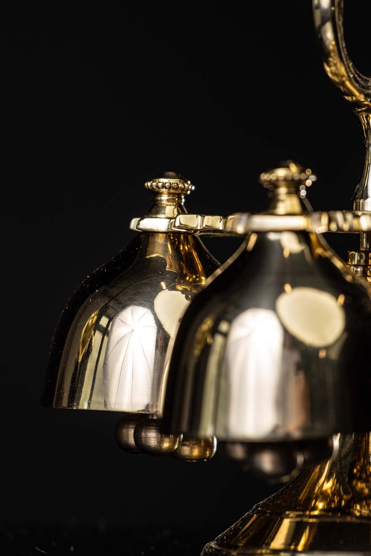 Side close-up of quadruple brass bells showing polished bell cups and clappers